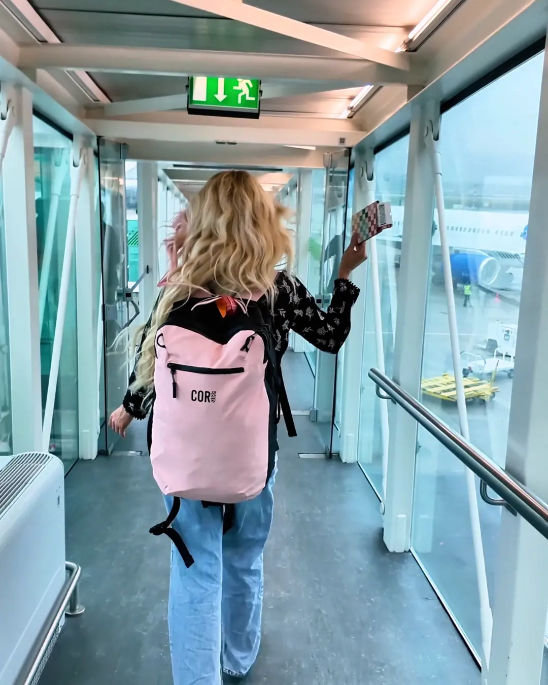 Woman walking through an airport jet bridge with a backpack while traveling to Türkiye