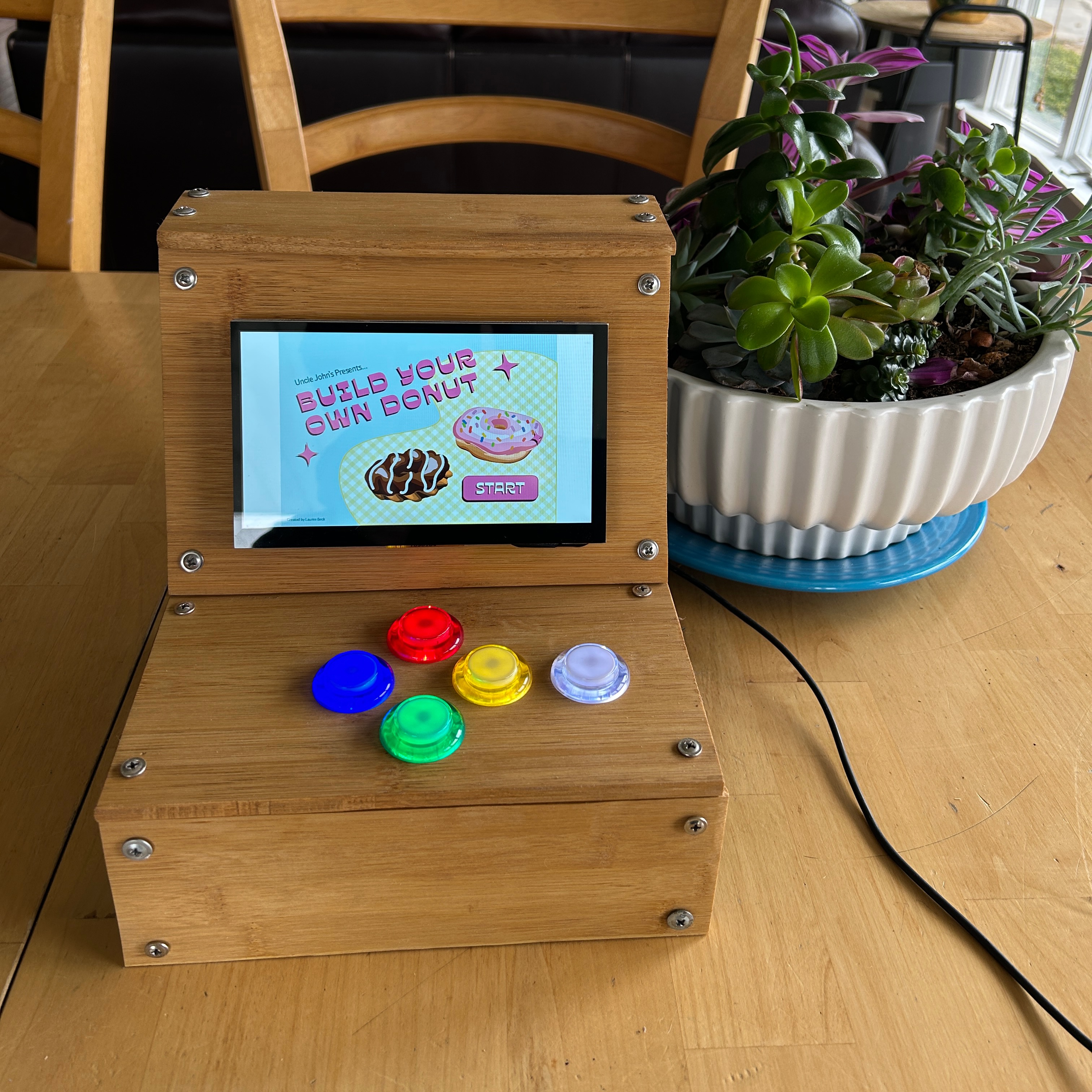 Small arcade cabinet with buttons and a screen with donuts