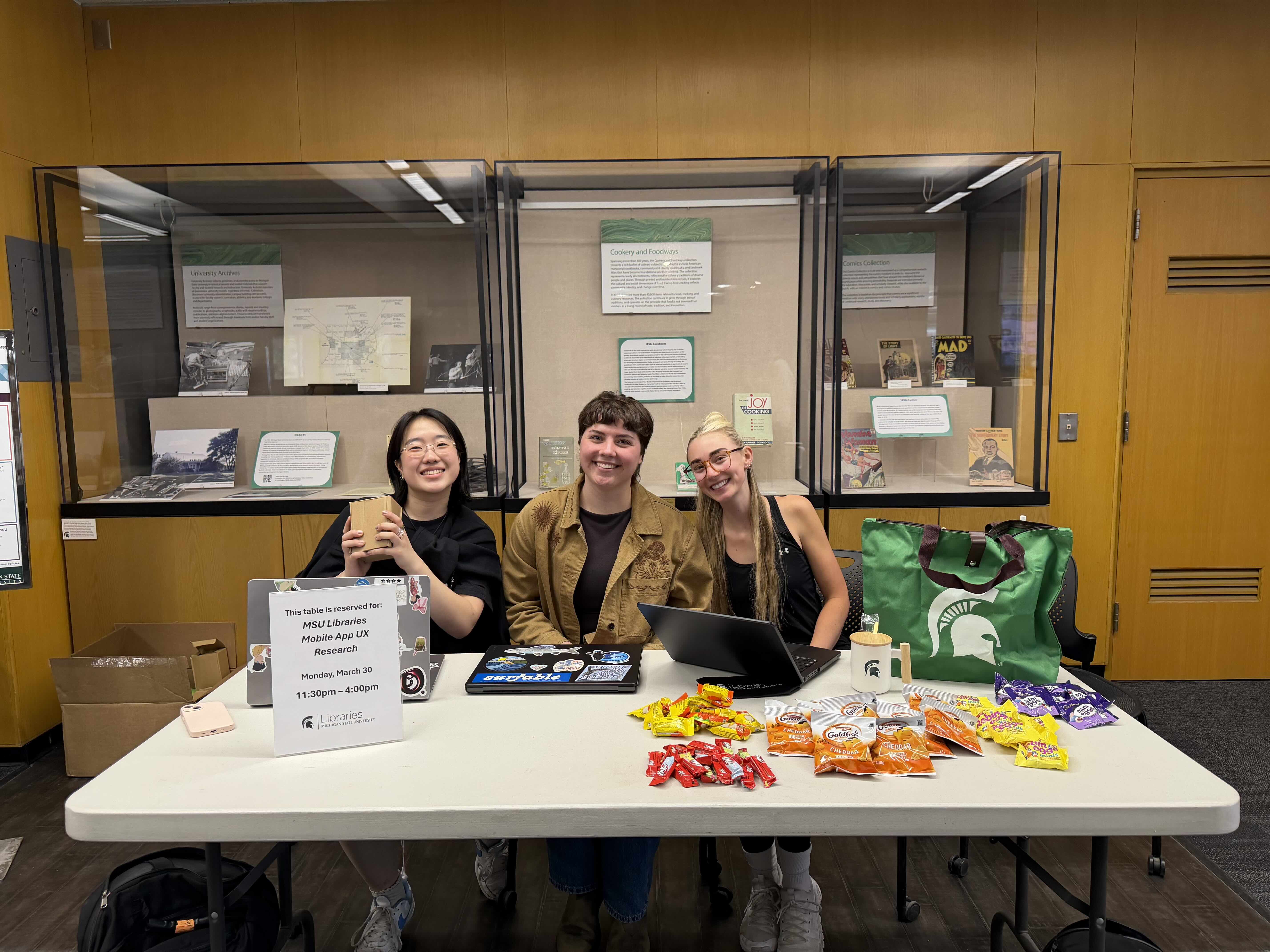 3 people sitting at a desk with incentives on table