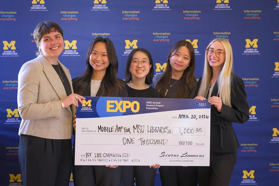 5 people holding up a check for $1,000