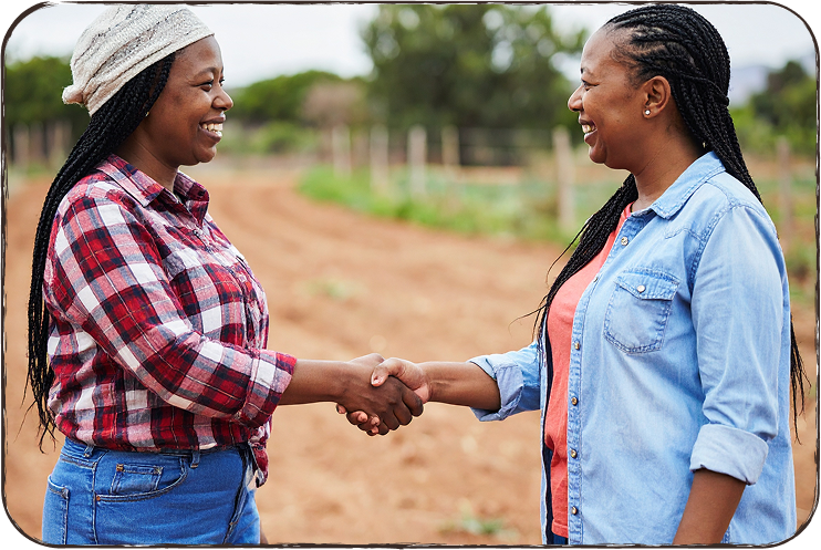 Two women shaking hands in a field.