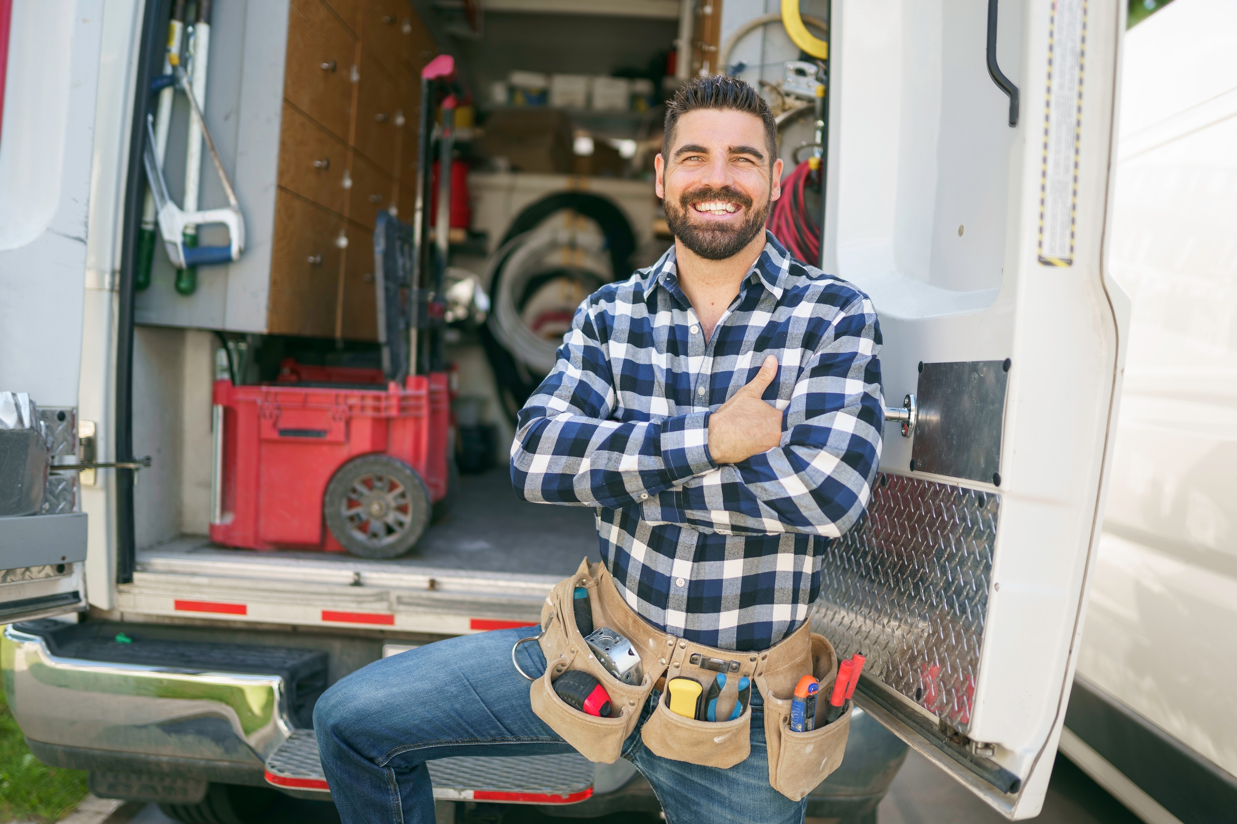 smiling HVAC tech in plaid shirt at back of truck