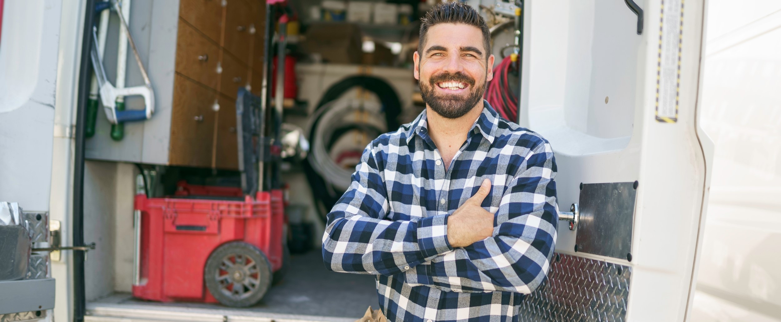 smiling HVAC tech in plaid shirt at back of truck