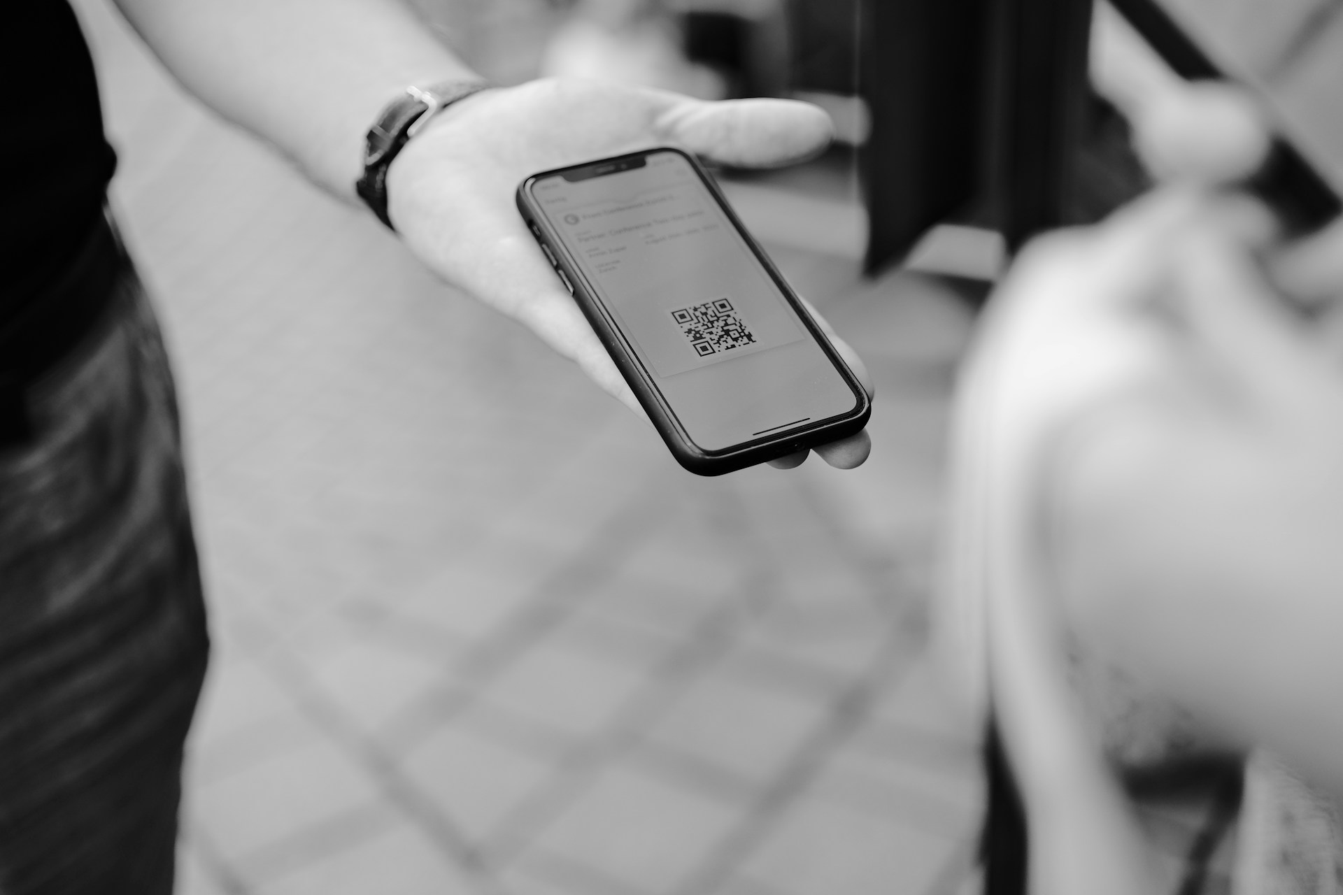 black and white image of a man showing a QR code to someone