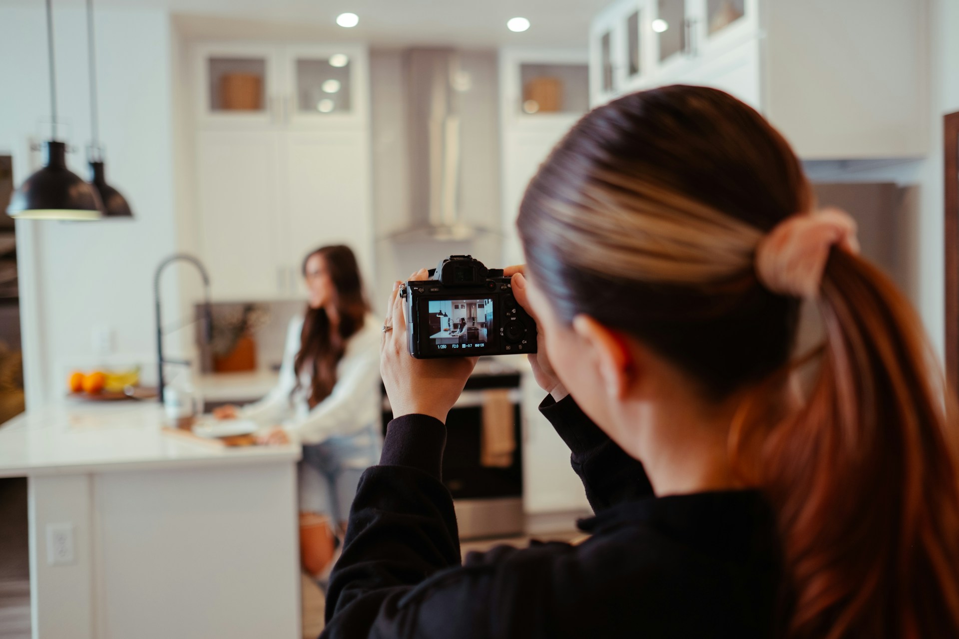 woman taking a photo of another woman in a kitchen