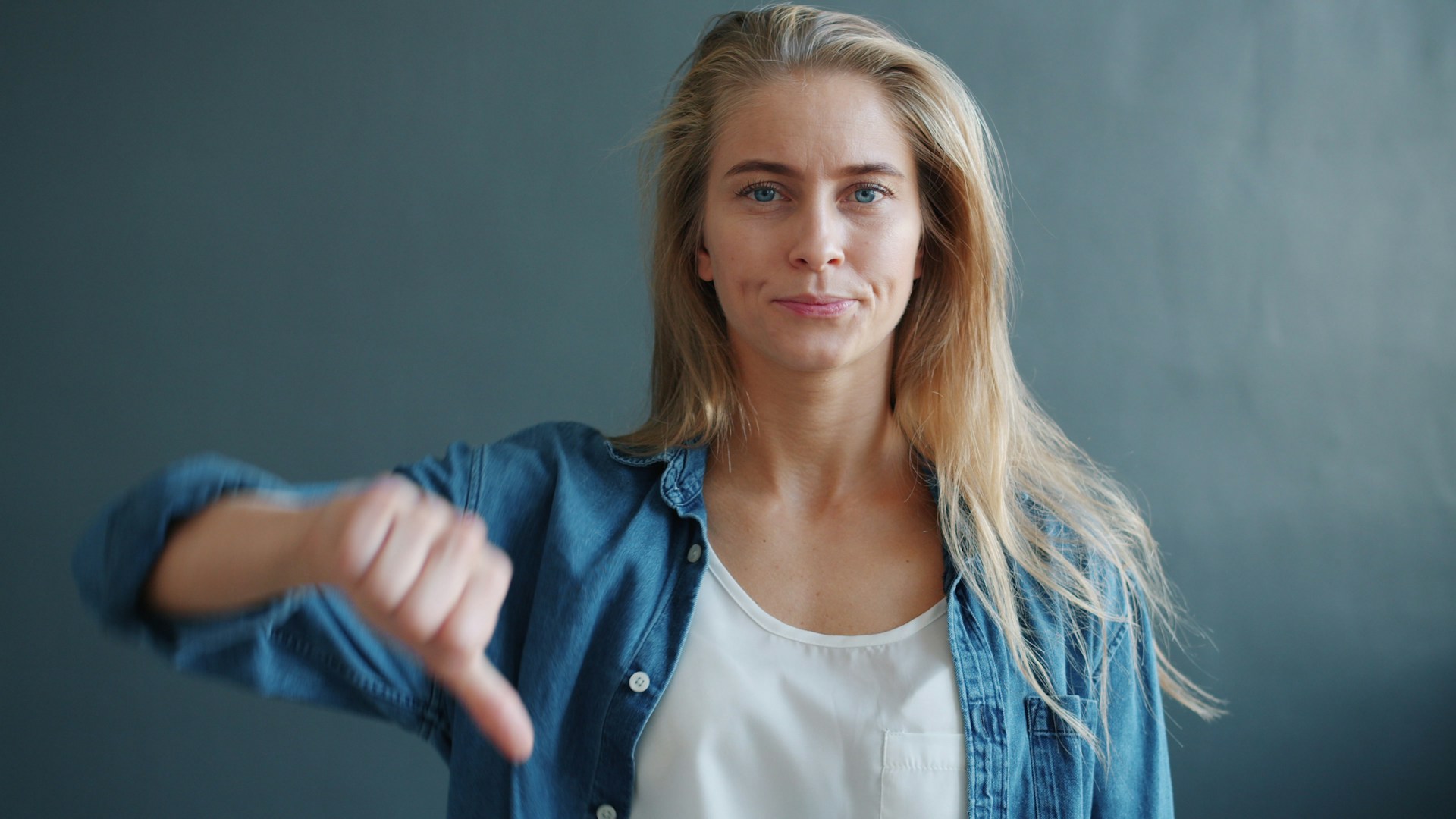 blonde woman with thumbs down in blue shirt 