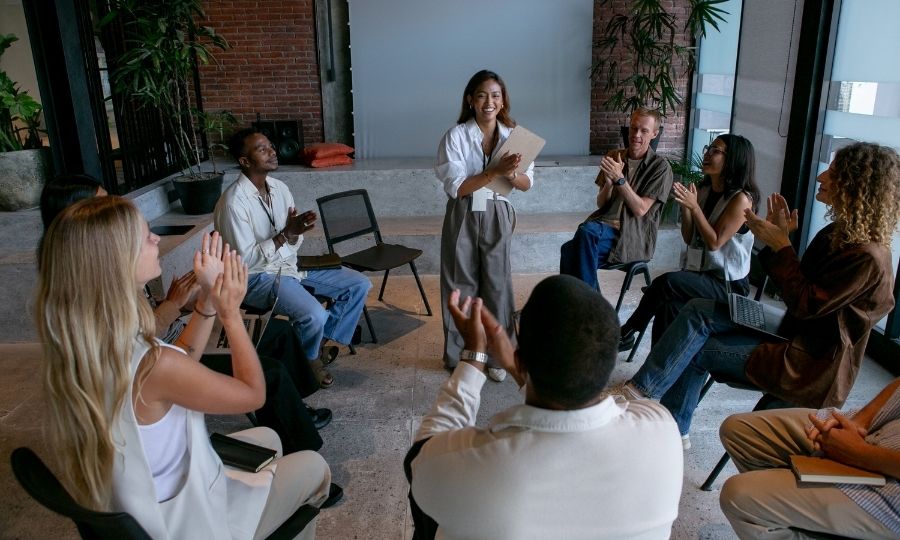 A group of people clapping in a circle, emphasizing soft skills as an underrated advantage for AI-proof USA careers.