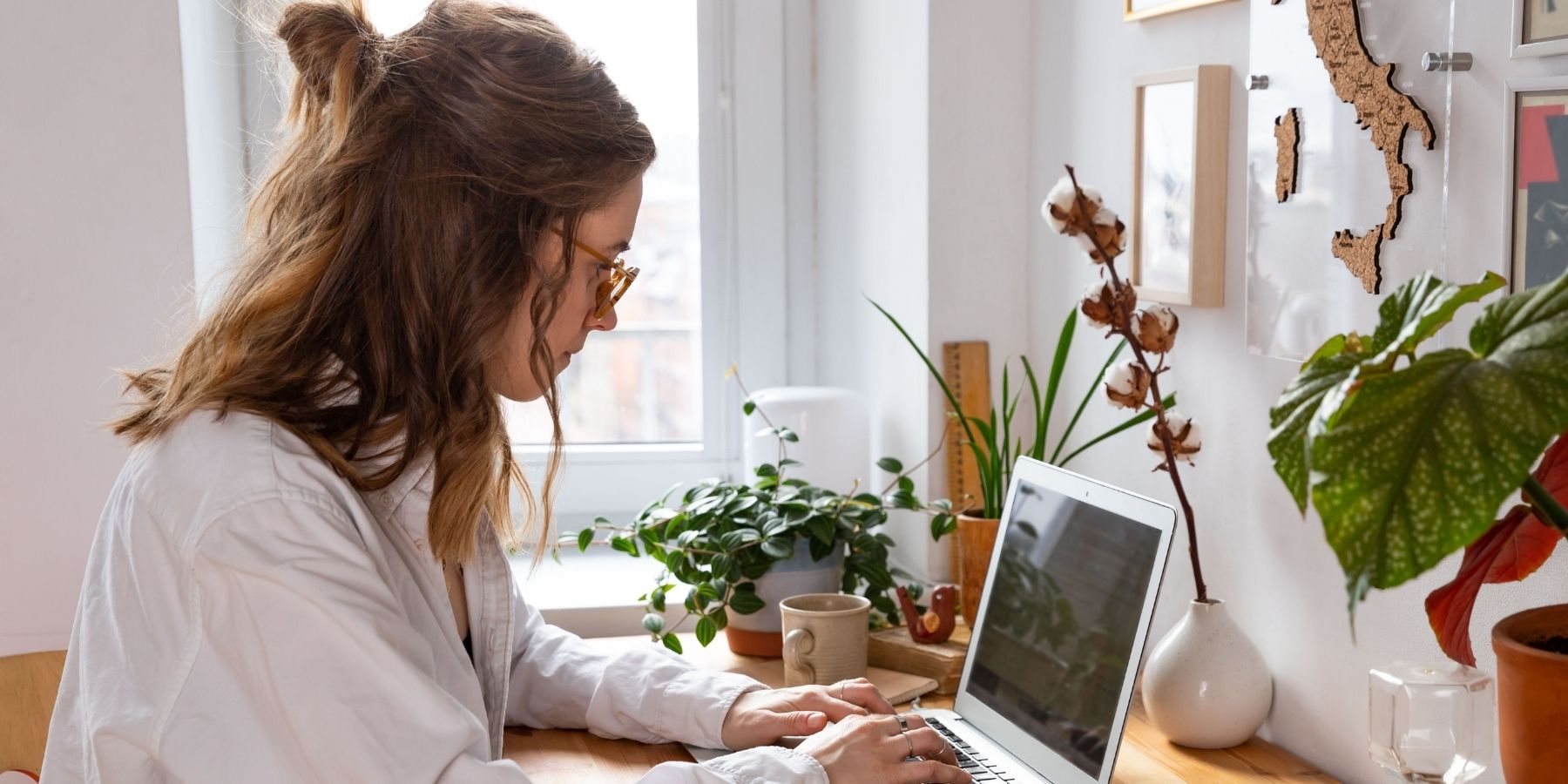 A woman on her laptop learning AI skills with plants on the desk.