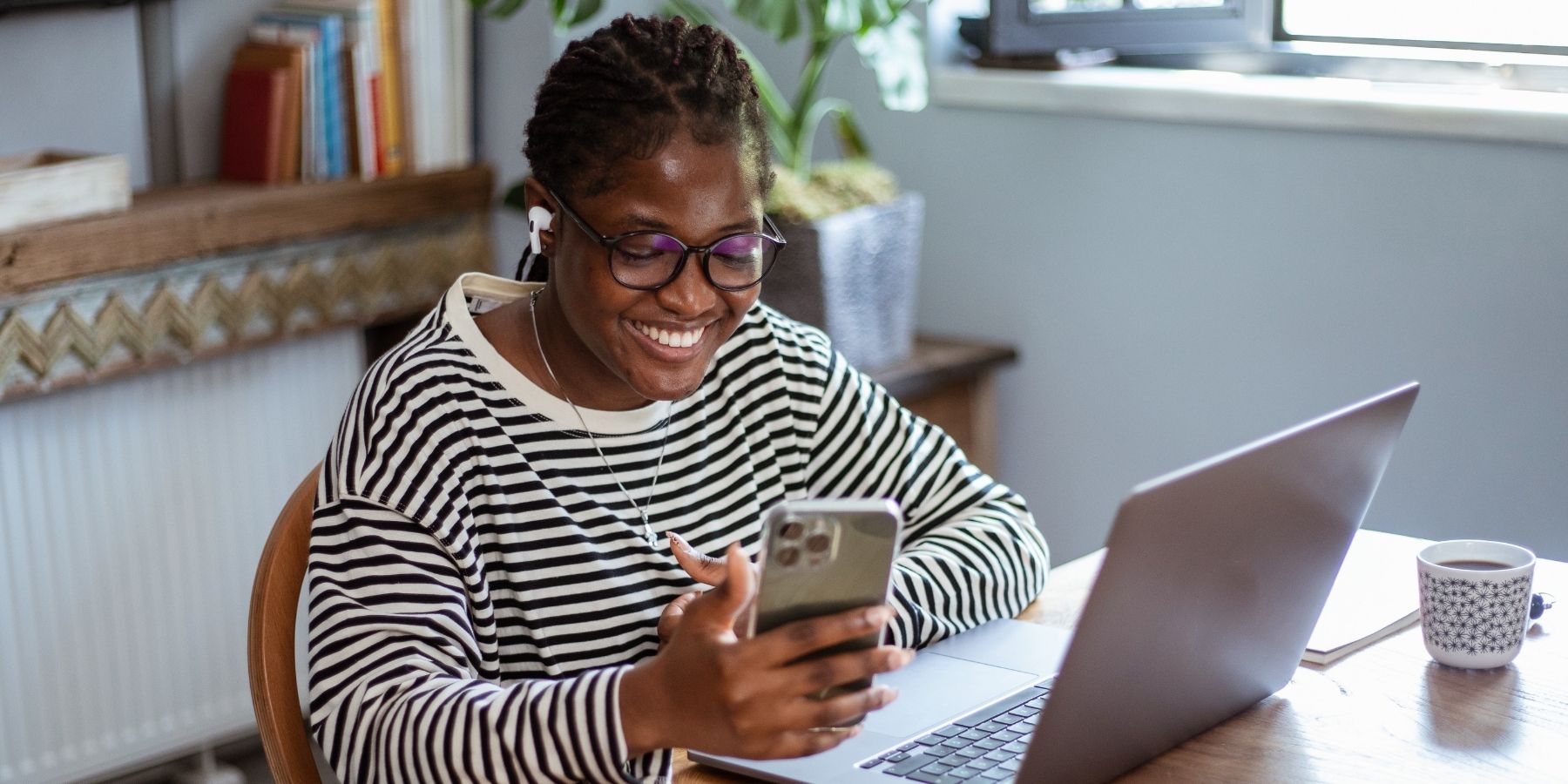 Person working at laptop with phone in 2025, thriving in AI-driven remote careers