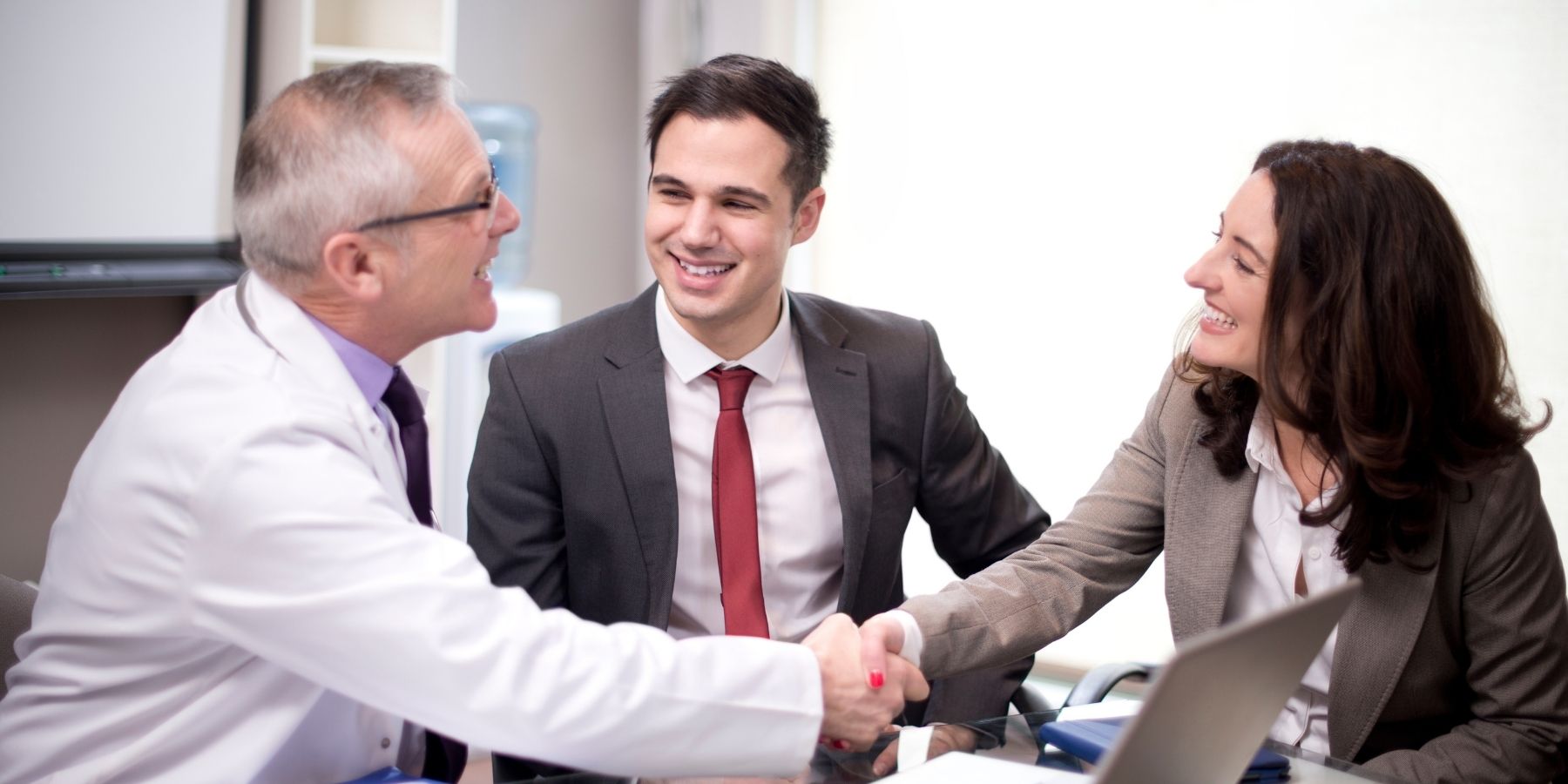 People shaking hands in meeting in 2025, overseeing AI for future-resistant jobs