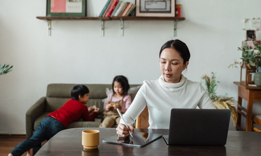 A woman working on a laptop with children, mastering essential AI-proof skills for future-proof freelance careers in the USA.