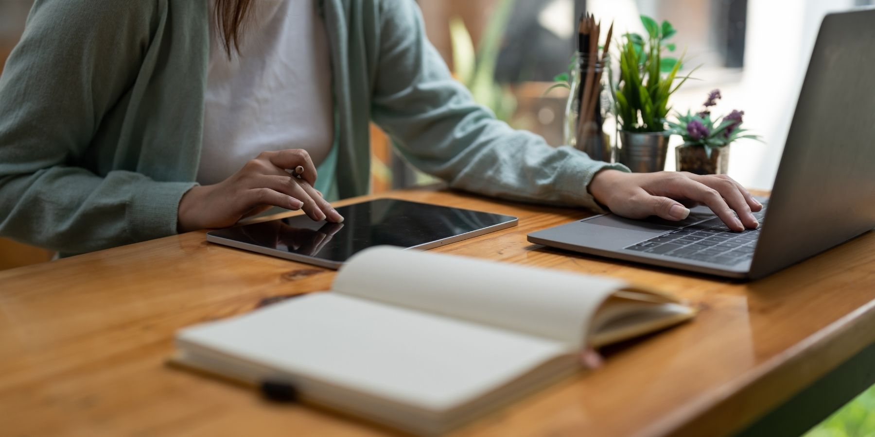 Freelancer using a laptop and tablet with a notebook, representing skills to future-proof a career.