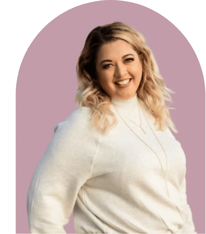 Smiling woman with curly blonde hair wearing a cream sweater and gold necklaces, against a mauve circle background.