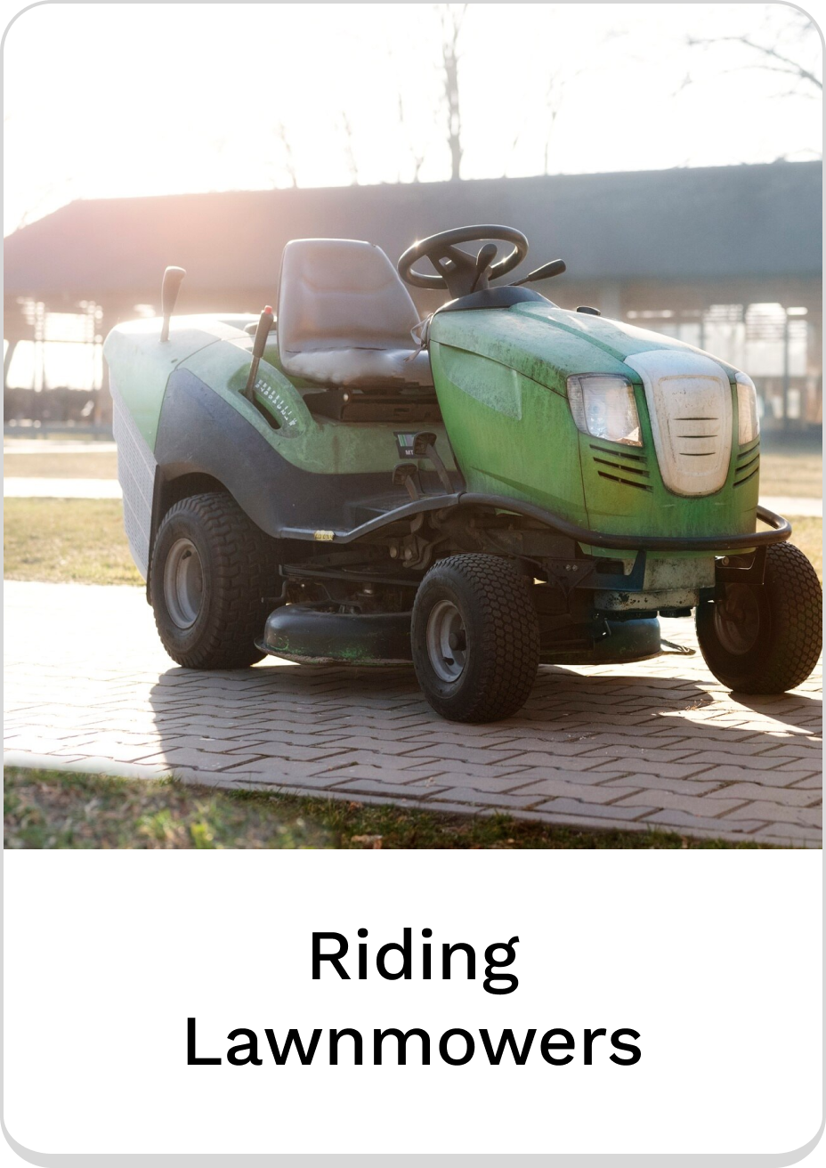 Green riding lawnmower parked on a brick pathway in sunlight.