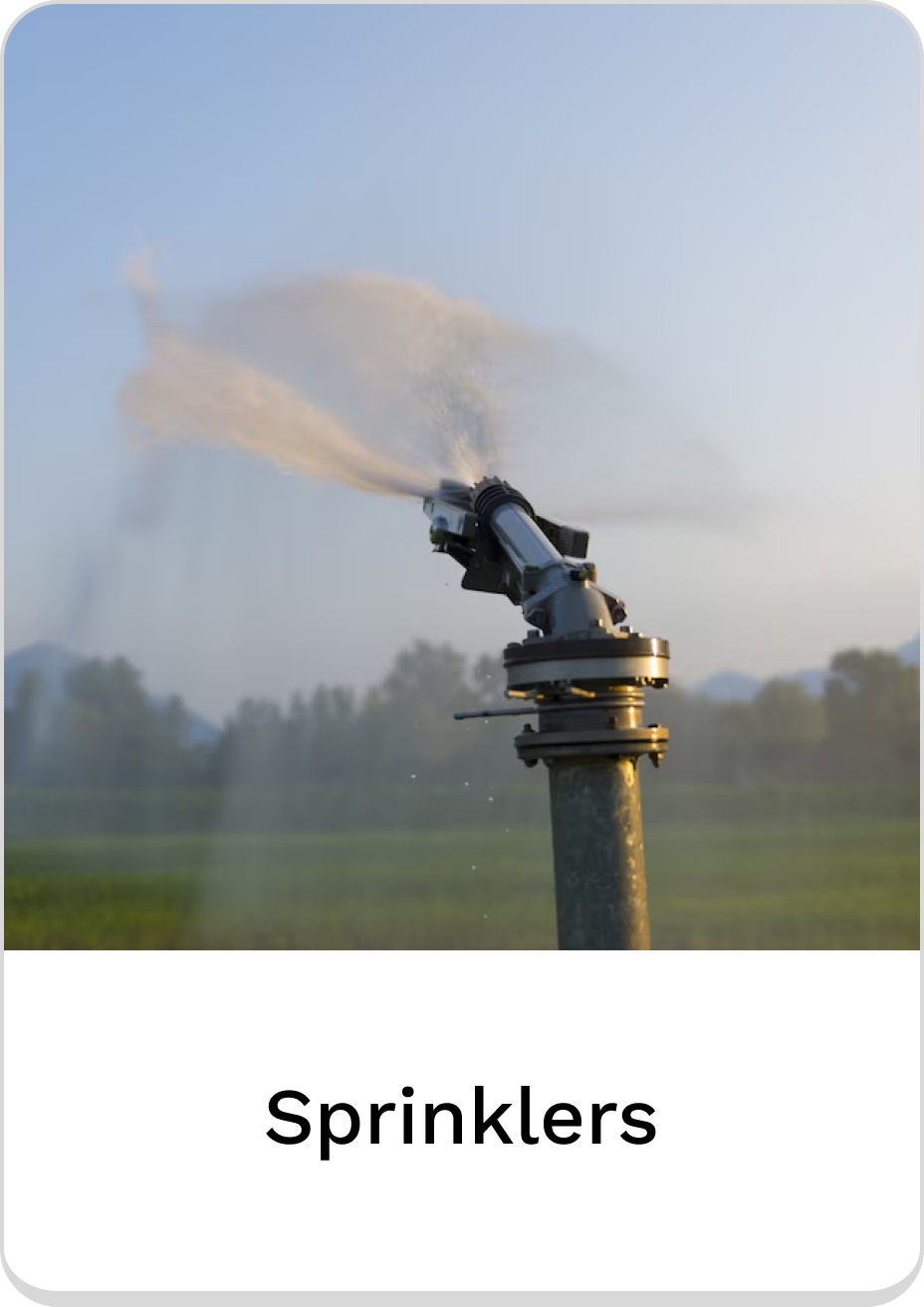 Automatic sprinklers watering green fields under a clear sky.
