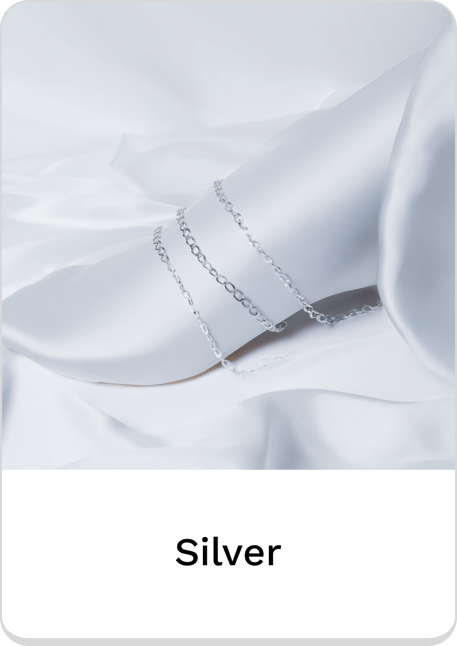 Elegant silver ankle chain adorning a delicate foot on soft fabric.