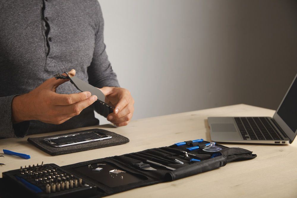 Technician repairing a smartphone screen with precision tools, illustrating how repair ecosystems support product warranty claims
