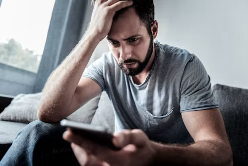Frustrated customer reading a generic AI support reply on his phone after a warranty claim goes wrong