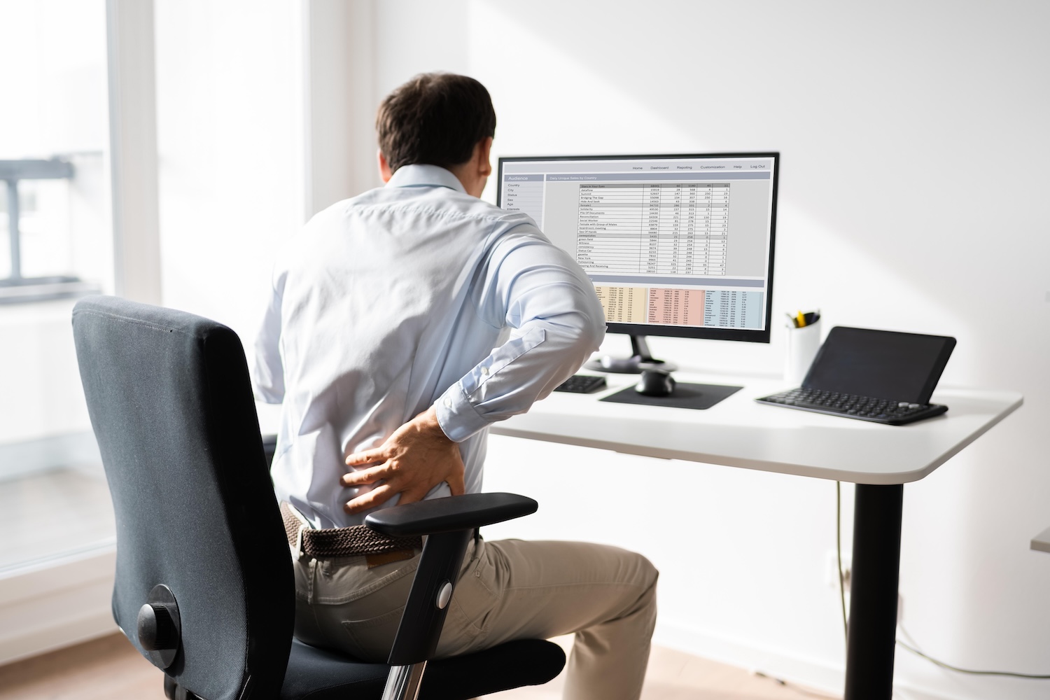 A man sits at his desk and has back pain