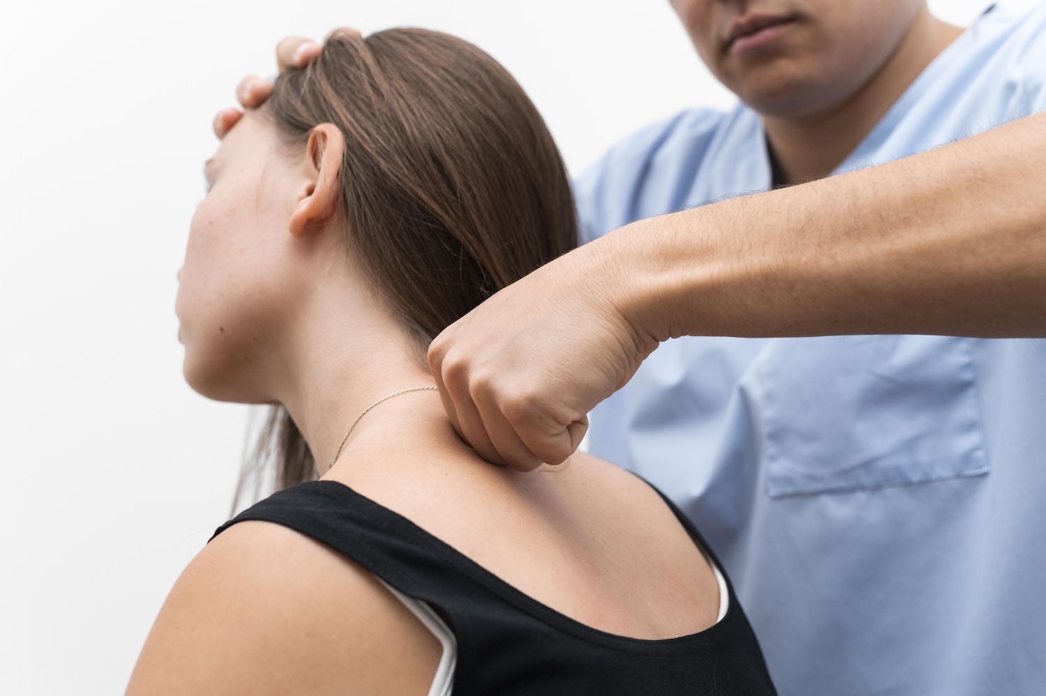Physiotherapeut mobilisiert die Halswirbelsäule einer Patientin während der Behandlung