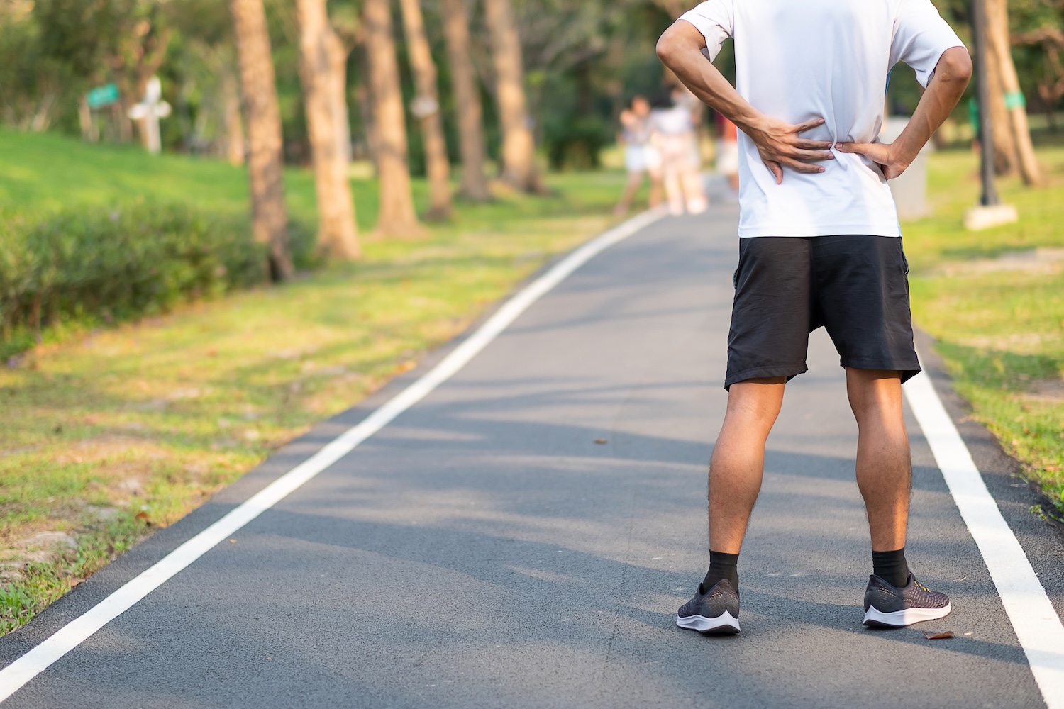 Mann beim Joggen bleibt stehen, weil er Hüftschmerzen hat.