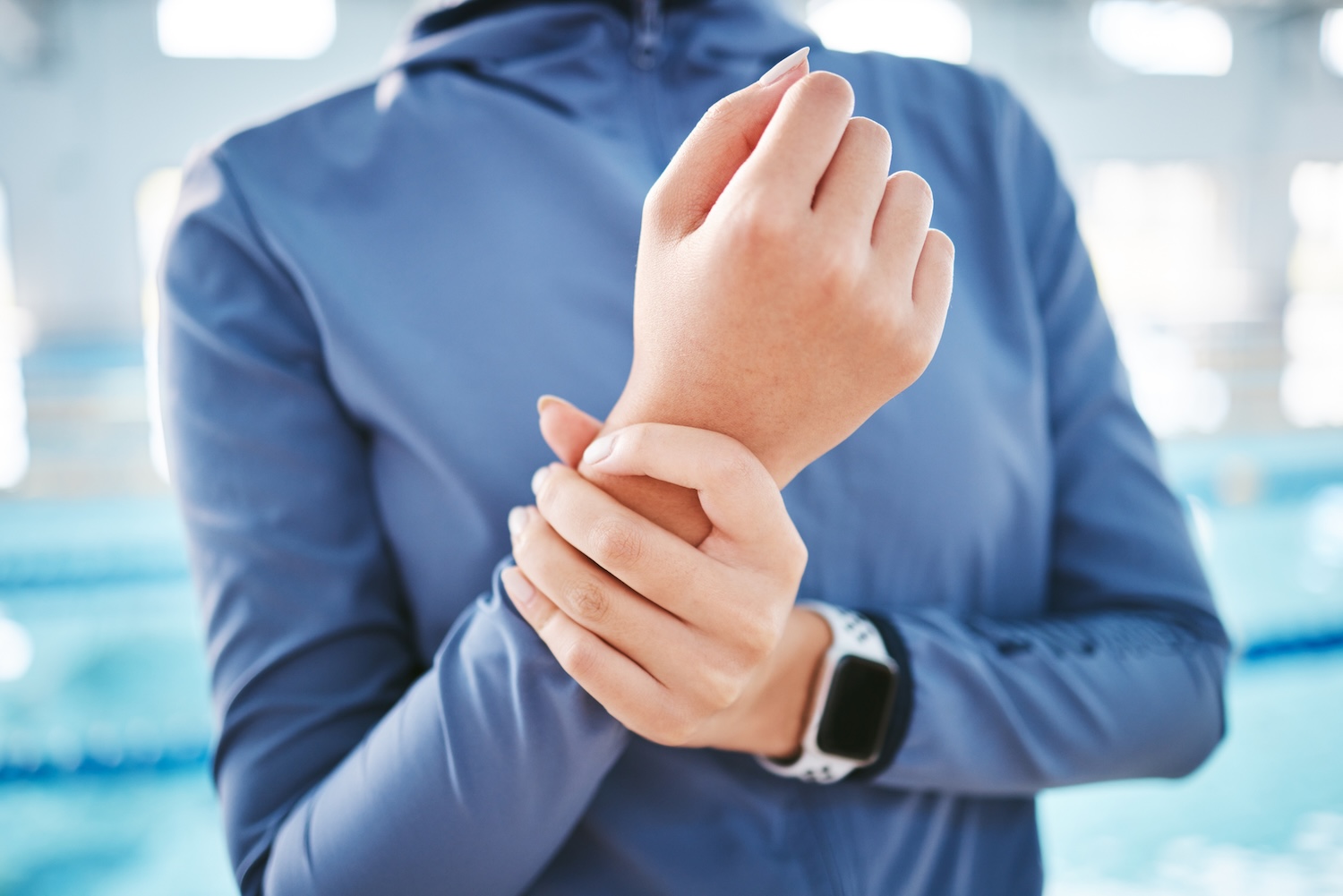 A woman in sportswear holding her wrist.