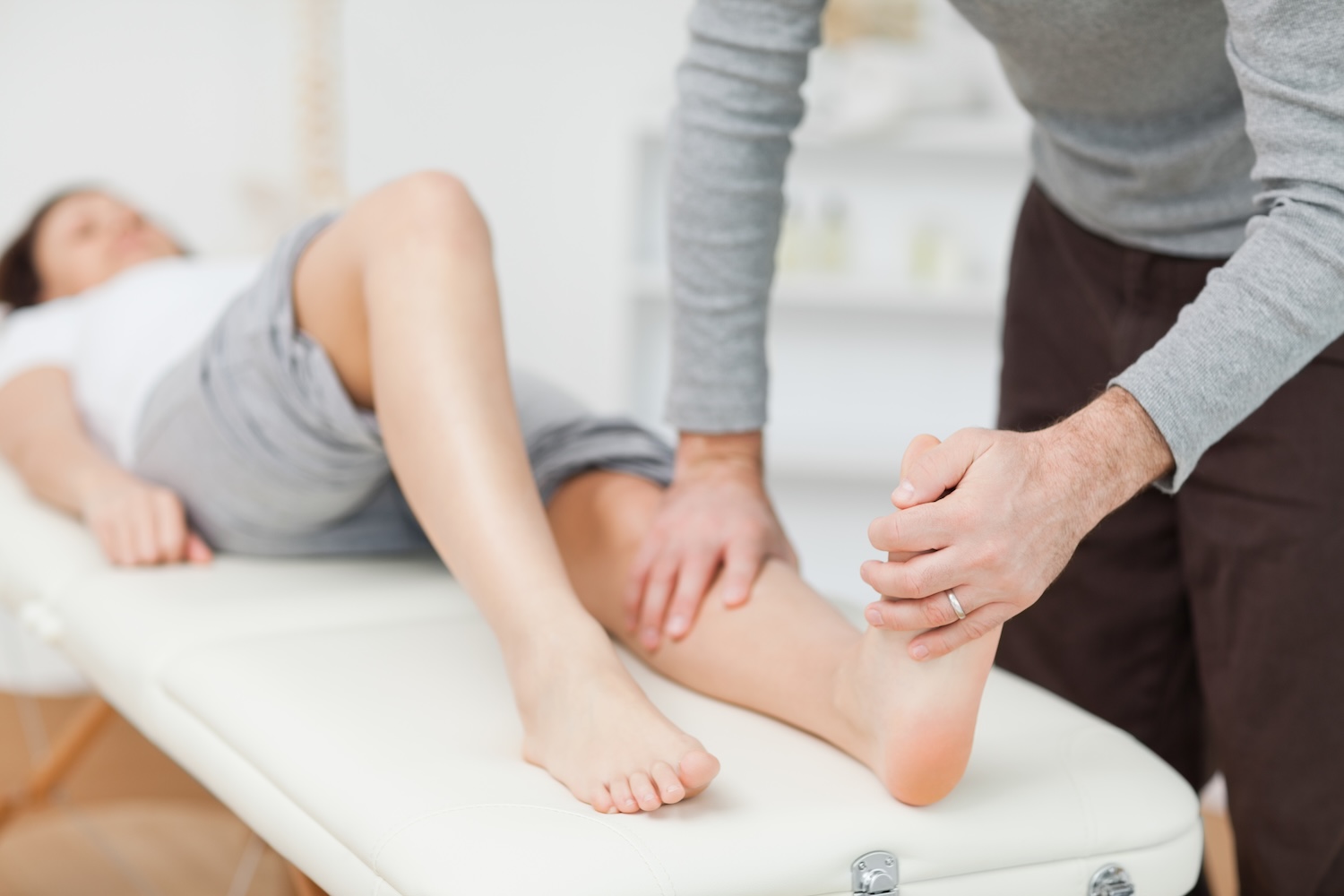 Eine Frau liegt und lässt ihre Fusschmerzen bei der Physiotherapie behandeln.