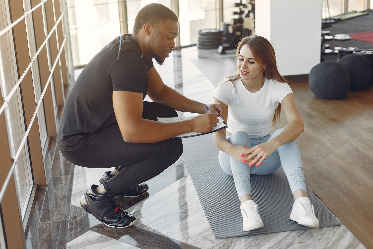 Physiotherapeut bespricht den Trainingsfortschritt mit einer Patientin im Trainingsraum