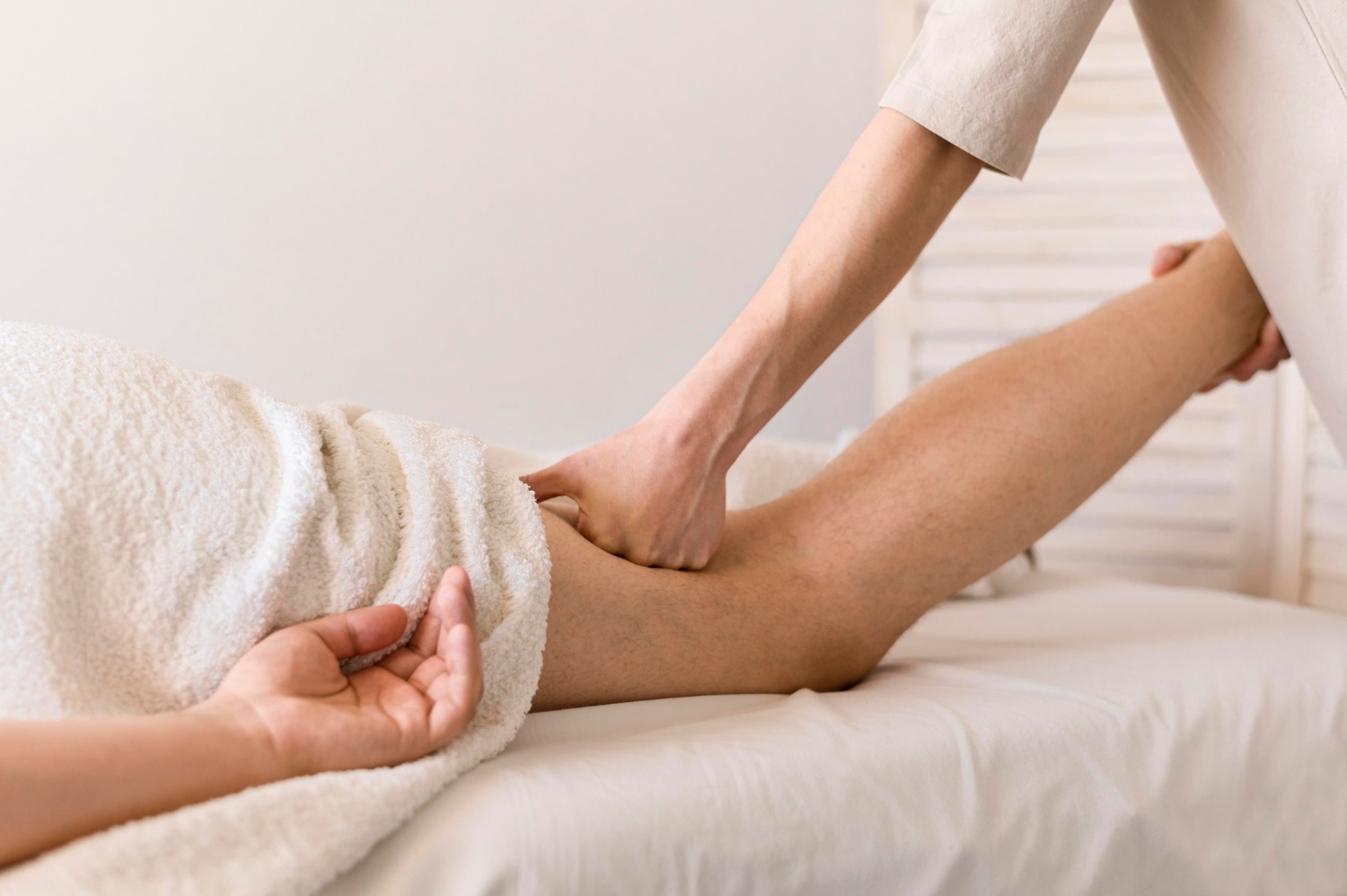 Physiotherapeut:in führt eine manuelle Lymphdrainage am Bein einer Patient:in durch