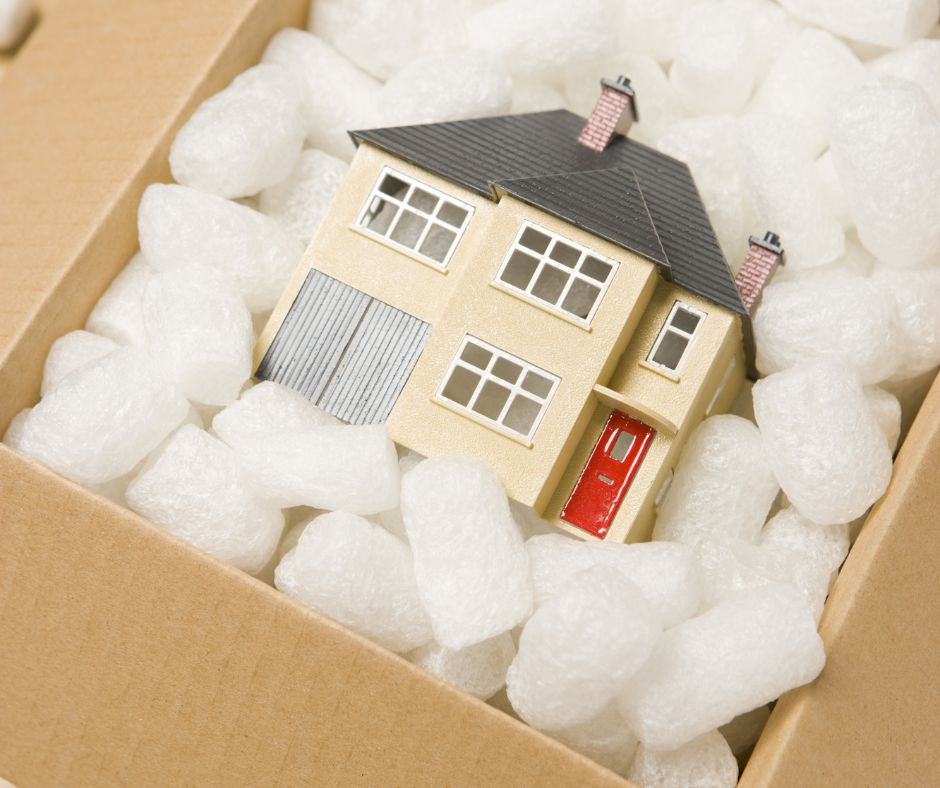 A toy house being backed into a box indicating (moving houses)