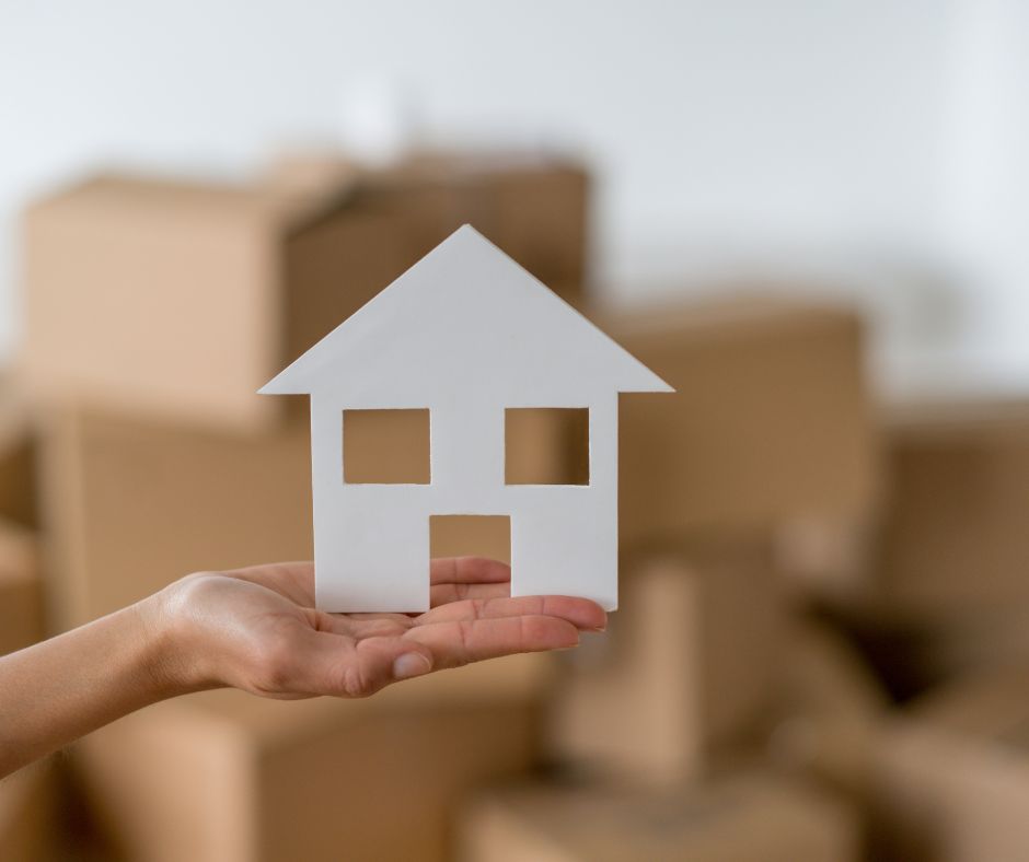 carboard cut out in shape of a home being held in a hand