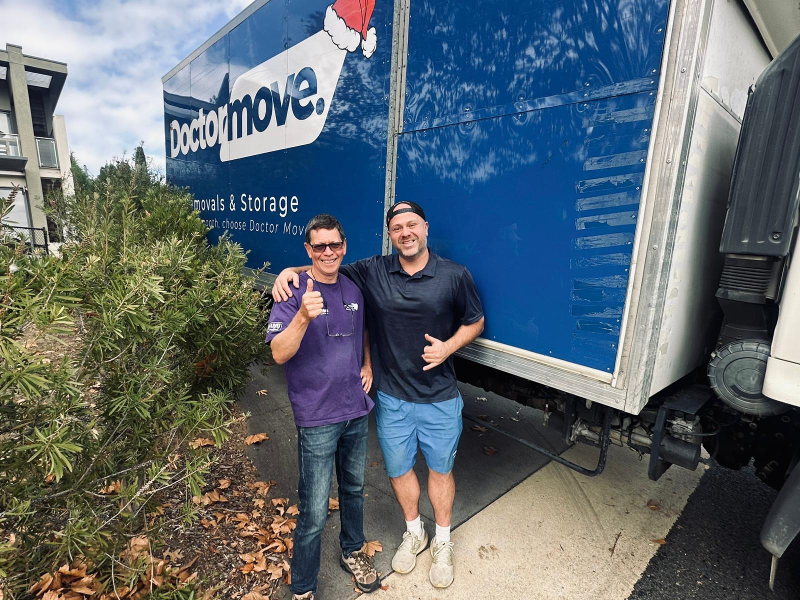Happy customer standing with team member from Doctor Move Canberra Removalists both standing in front of a doctor move truck