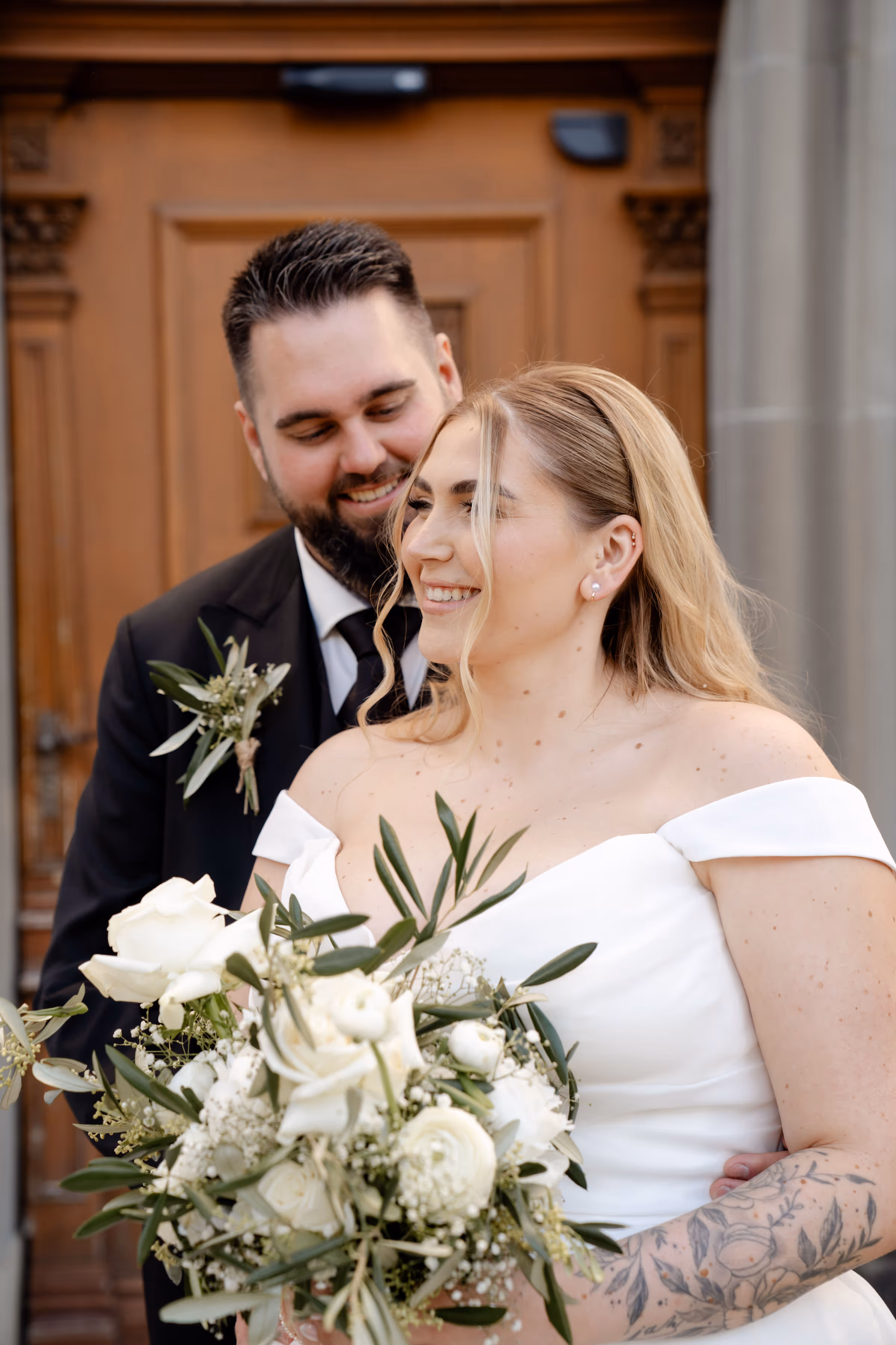 Glückliches Brautpaar feiert Traumhochzeit in der Schweiz, direkt am Rhein. Beide sind enorm entspannt, da die Hochzeit von einer professionellen Hochzeitsplanerin organisiert wurde. Die Braut hält Blumen in der Hand.