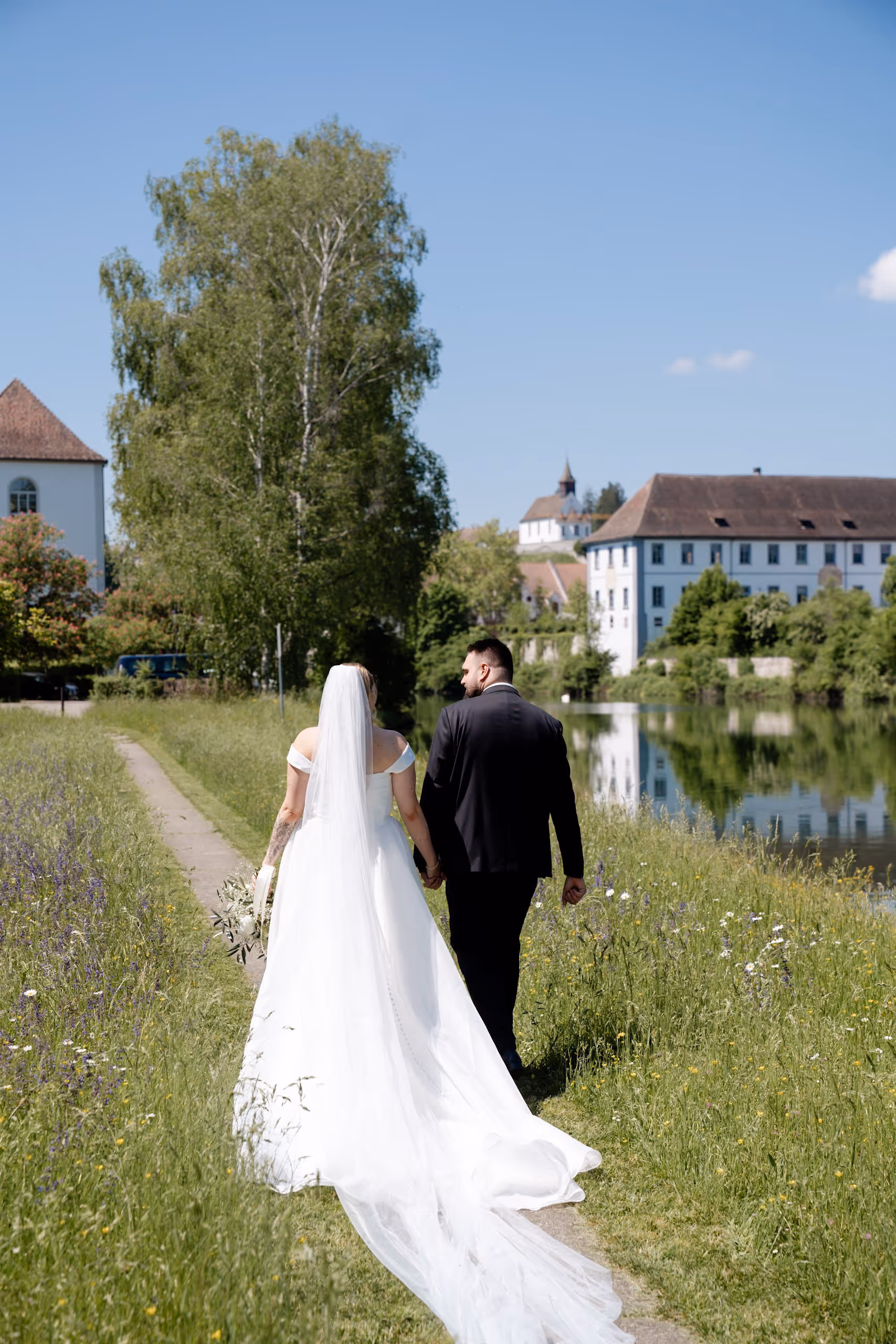 Glückliches Brautpaar feiert Traumhochzeit in der Schweiz. Beide sind enorm entspannt, da die Hochzeit von einer professionellen Hochzeitsplanerin organisiert wurde. Das Paar läuft einen romantischen Weg entlang.