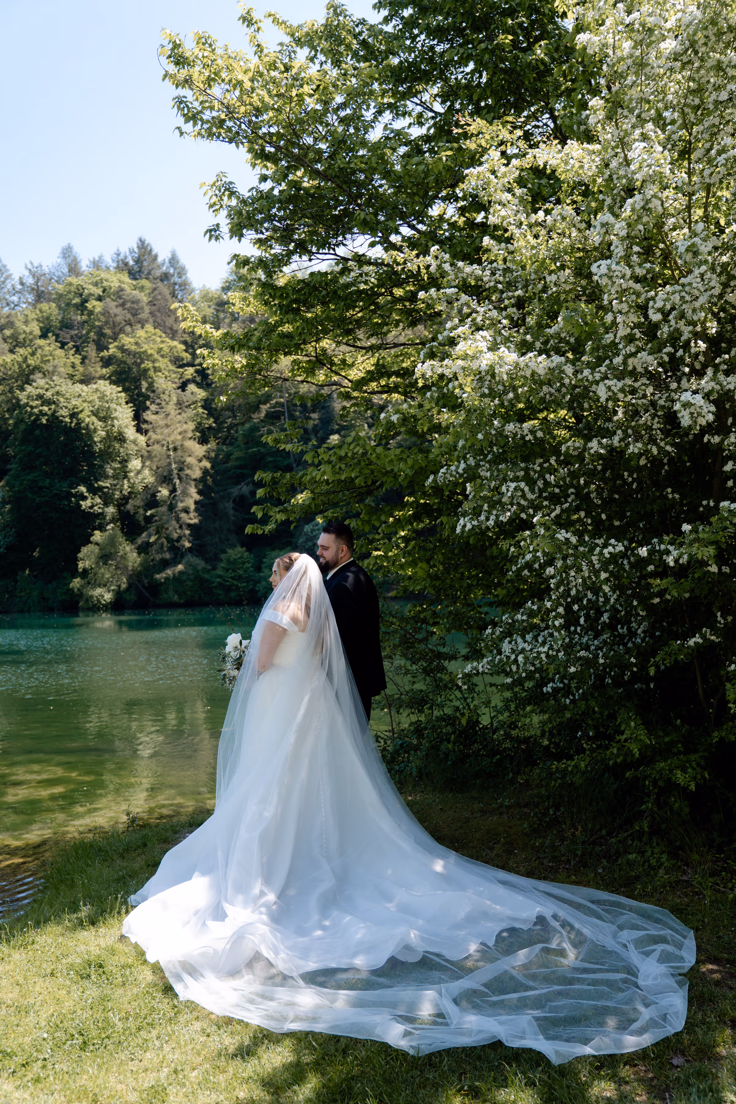 Glückliches Brautpaar feiert Traumhochzeit in der Schweiz, direkt am Rhein. Beide sind enorm entspannt, da die Hochzeit von einer professionellen Hochzeitsplanerin organisiert wurde. Die Braut trägt ein weisses Brautkleid.