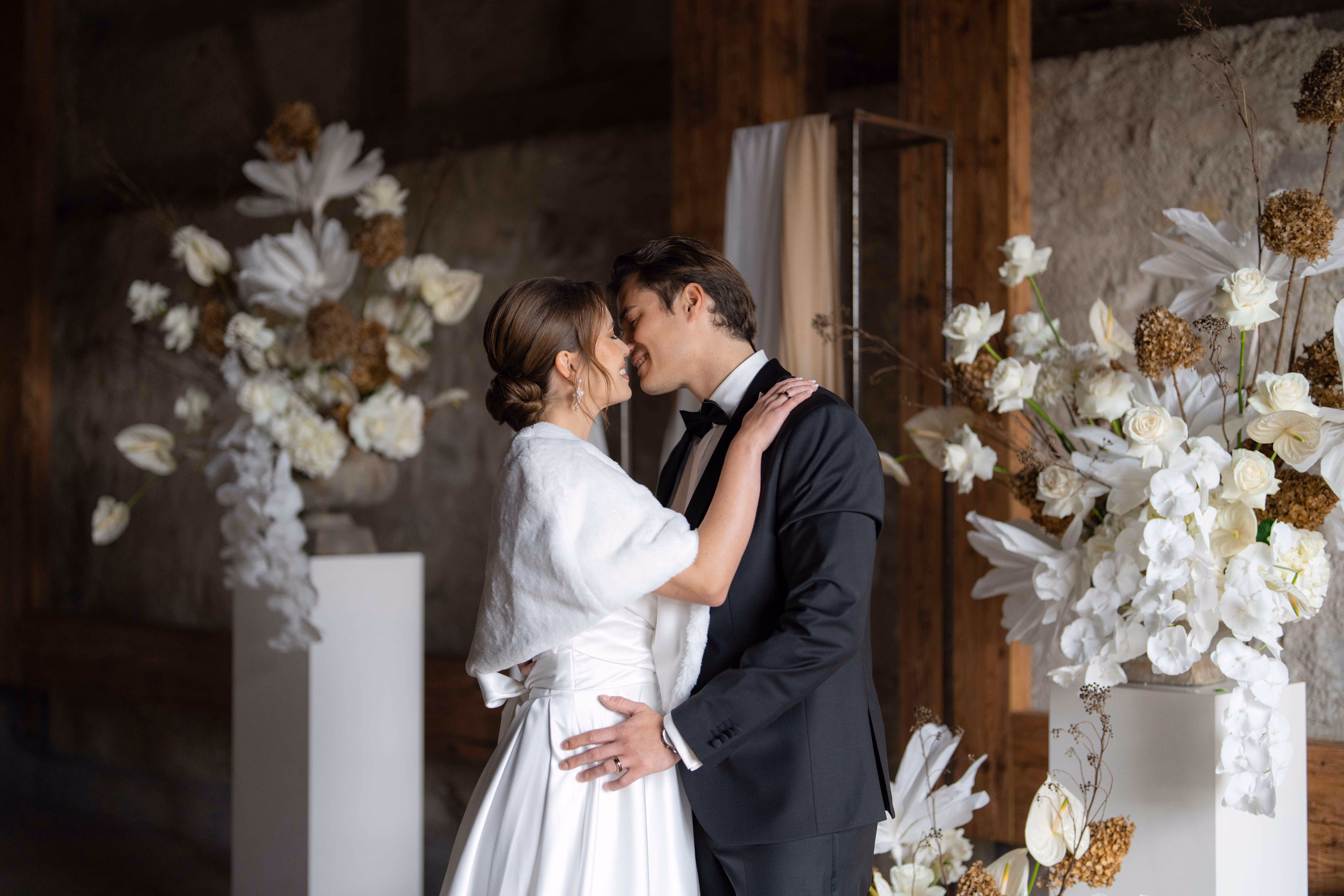 Bräutigam küsst Braut an Hochzeit in Schaffhausen. Blumen im Hintergrund.