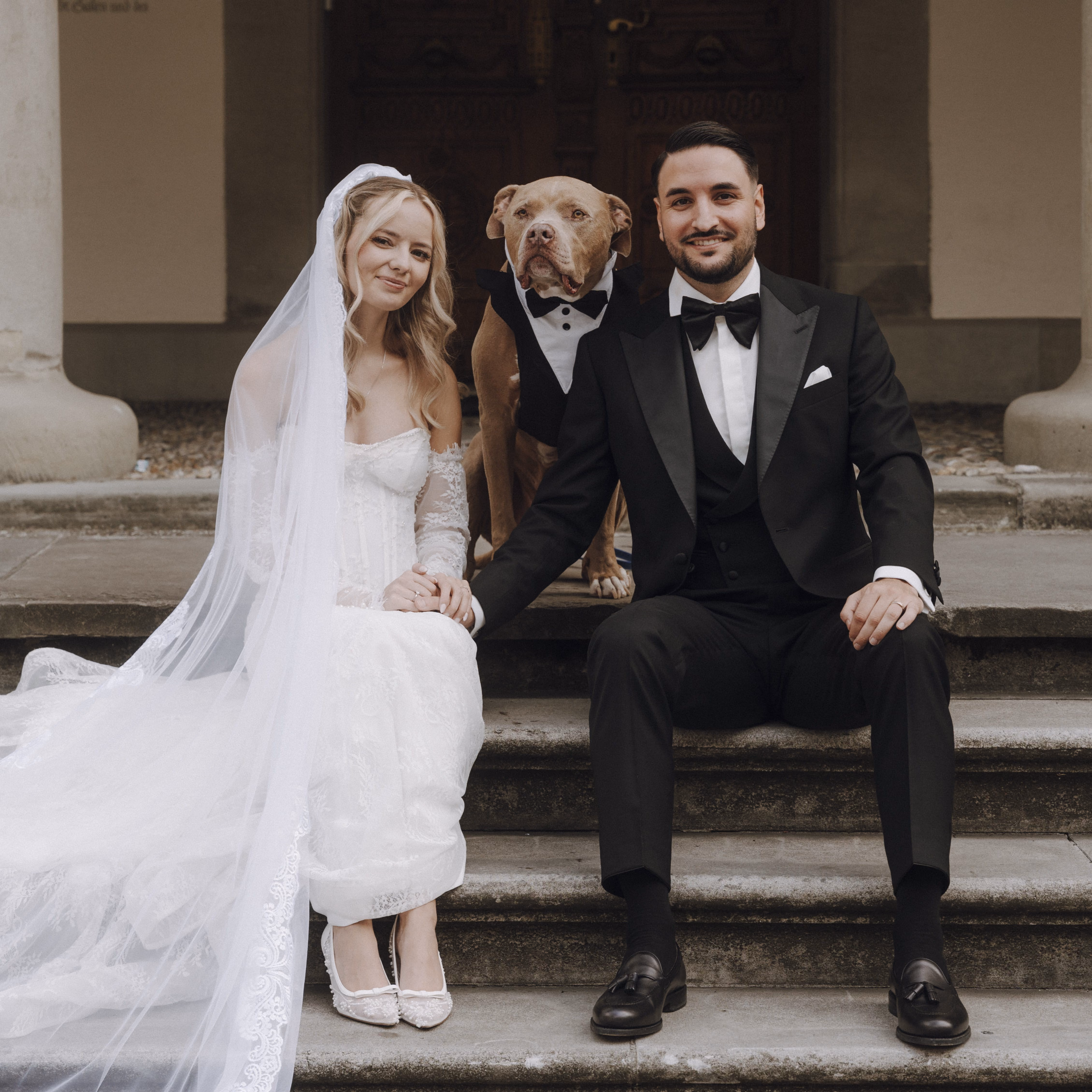 Ein Brautpaar an ihrer Hochzeit in Schaffhausen sitzt mit ihrem Hund auf einer Treppe
