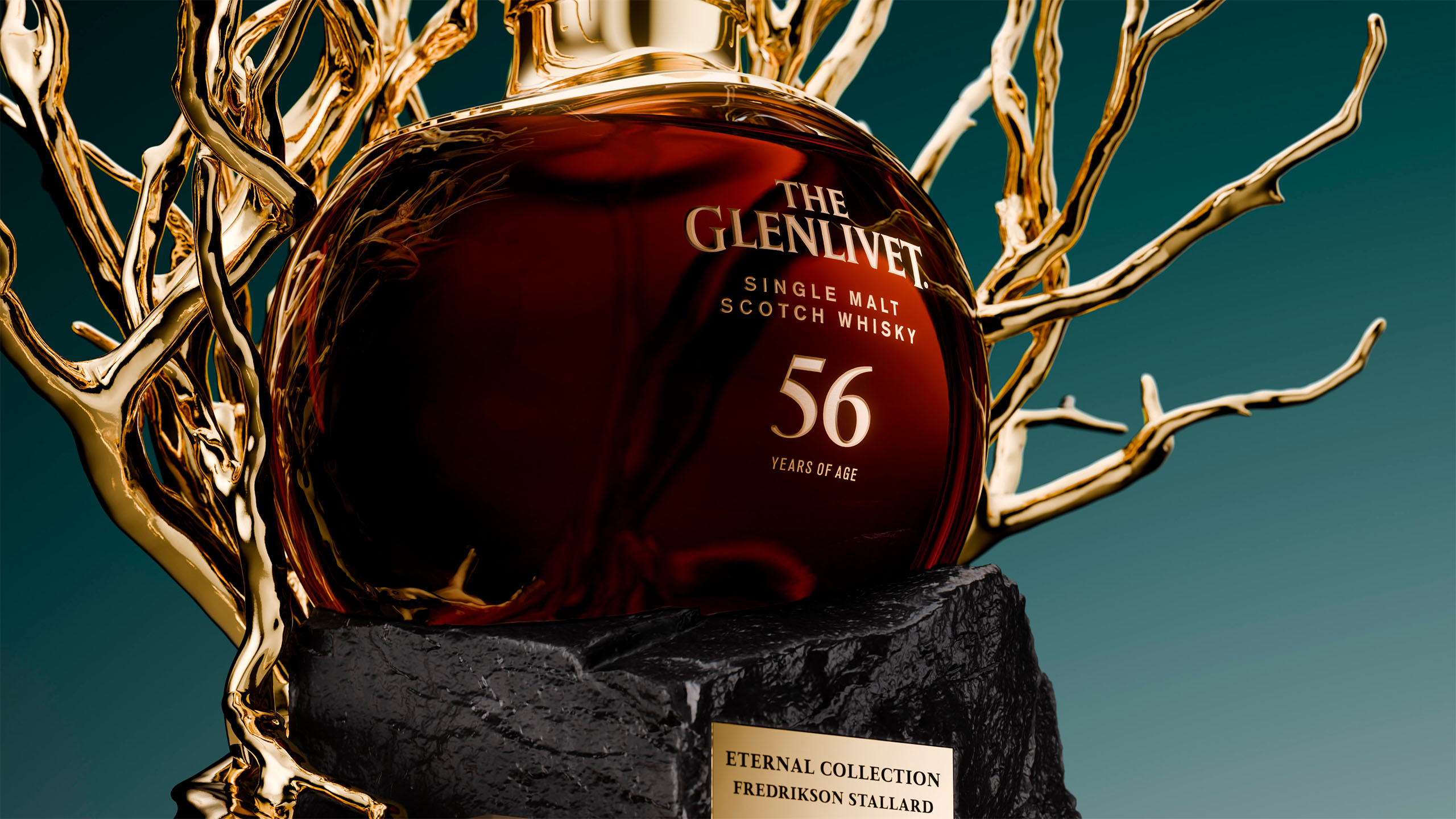 The Glenlivet 56 Year Old single malt whisky bottle cradled within sculptural gold branches on a dark stone base.