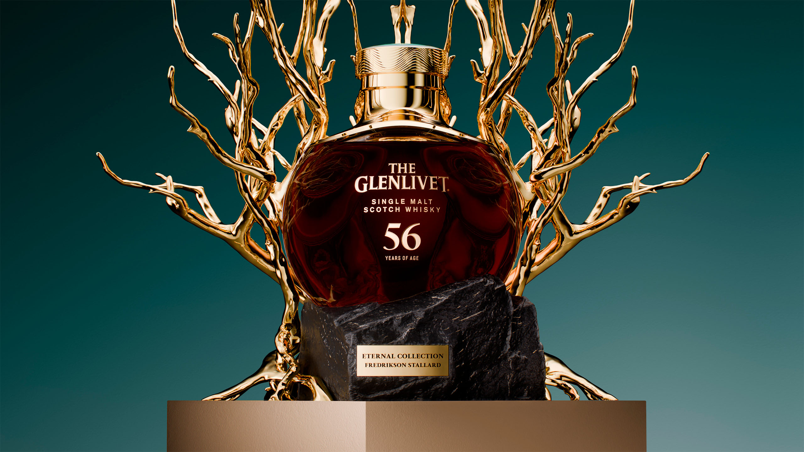 Front view of The Glenlivet 56 Year Old single malt whisky bottle framed by intricate gold branches on a pedestal.