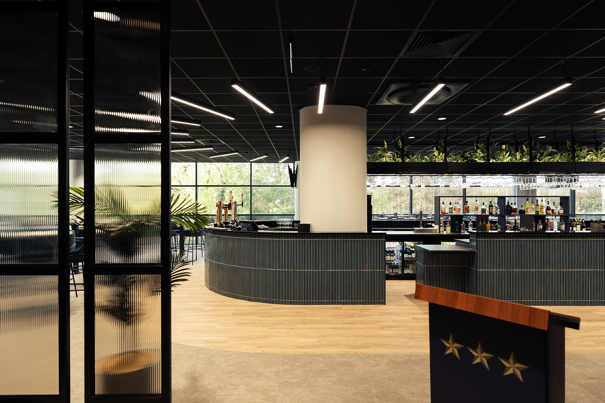 A directors lounge at Ipswich stadium with views to the pitch, showcasing interior design, furniture and bar