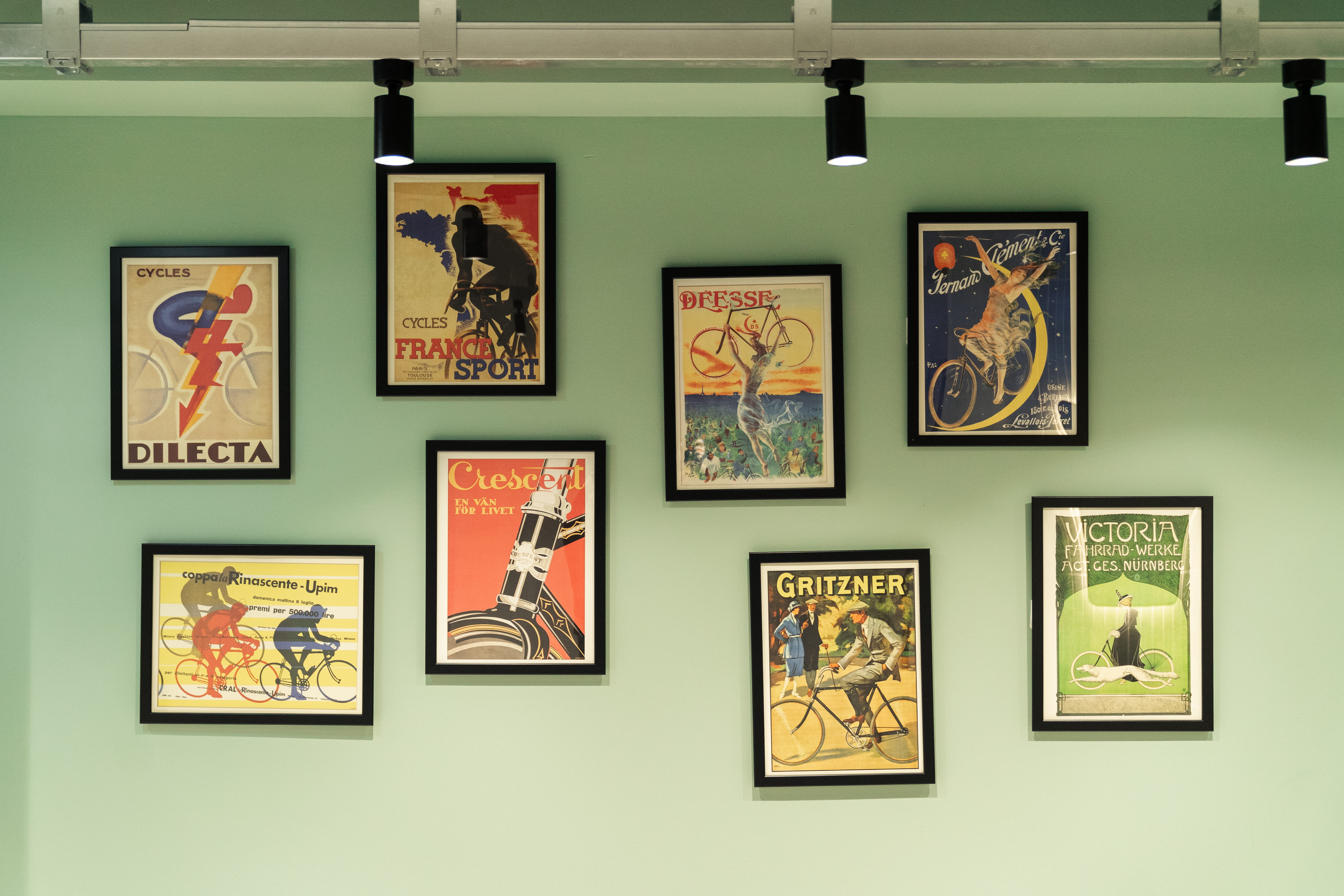 pale green wall with lots of photo frames on it