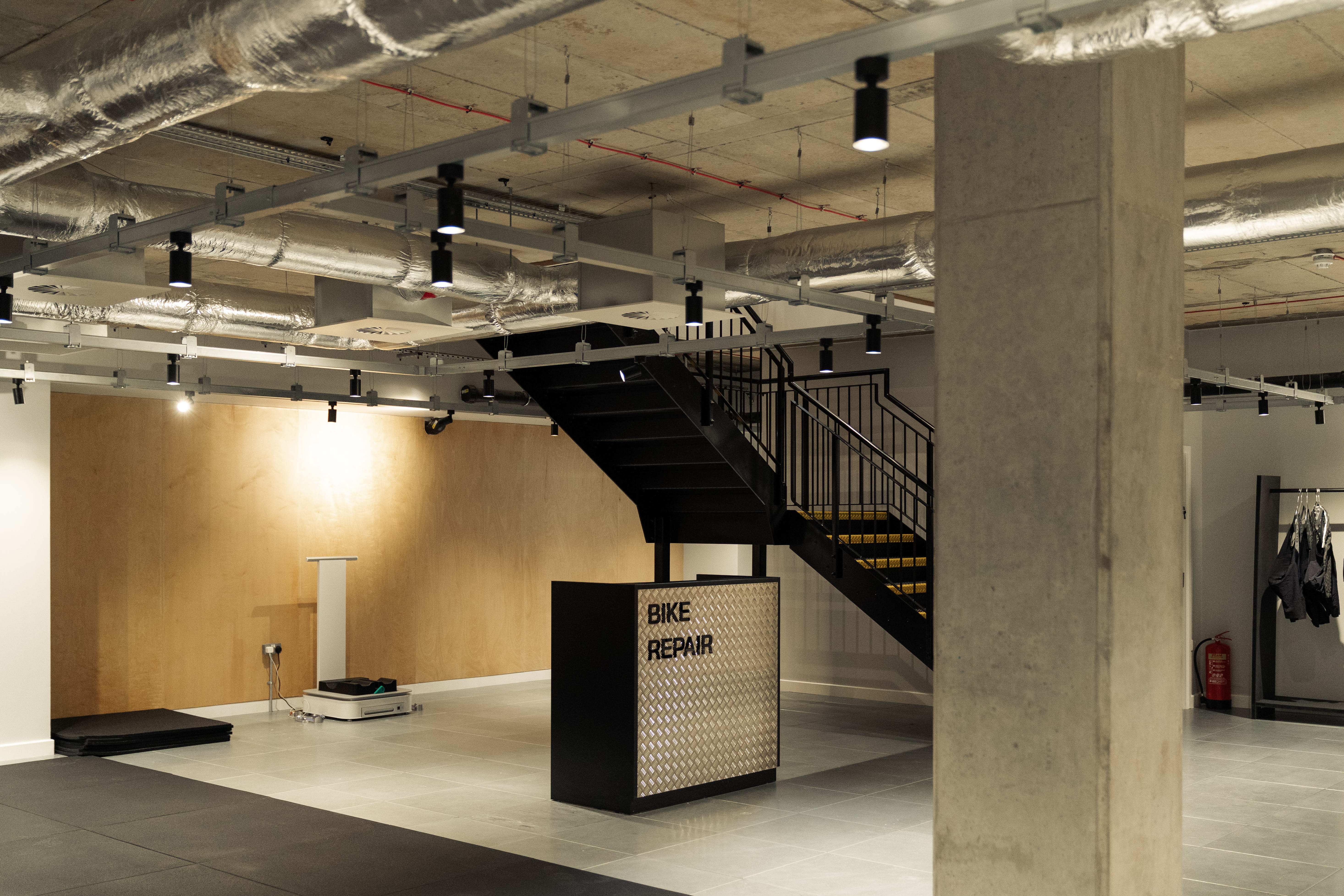 industrial looking area with concrete posts, and a small silver kiosk labelled 'bike repairs' in black writing