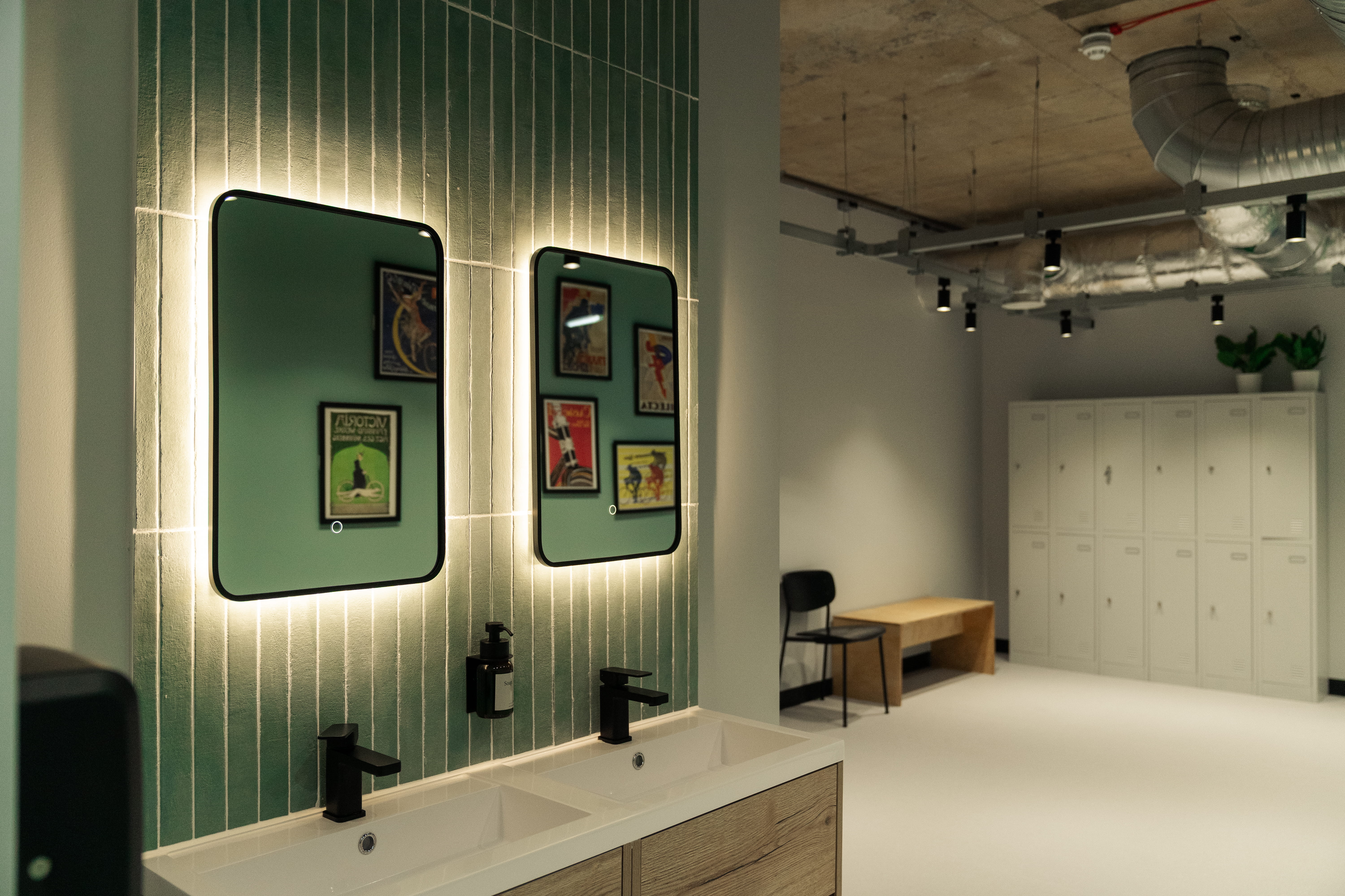 light up mirrors on blue bathroom tiles above concrete sinks, and close by to lockers