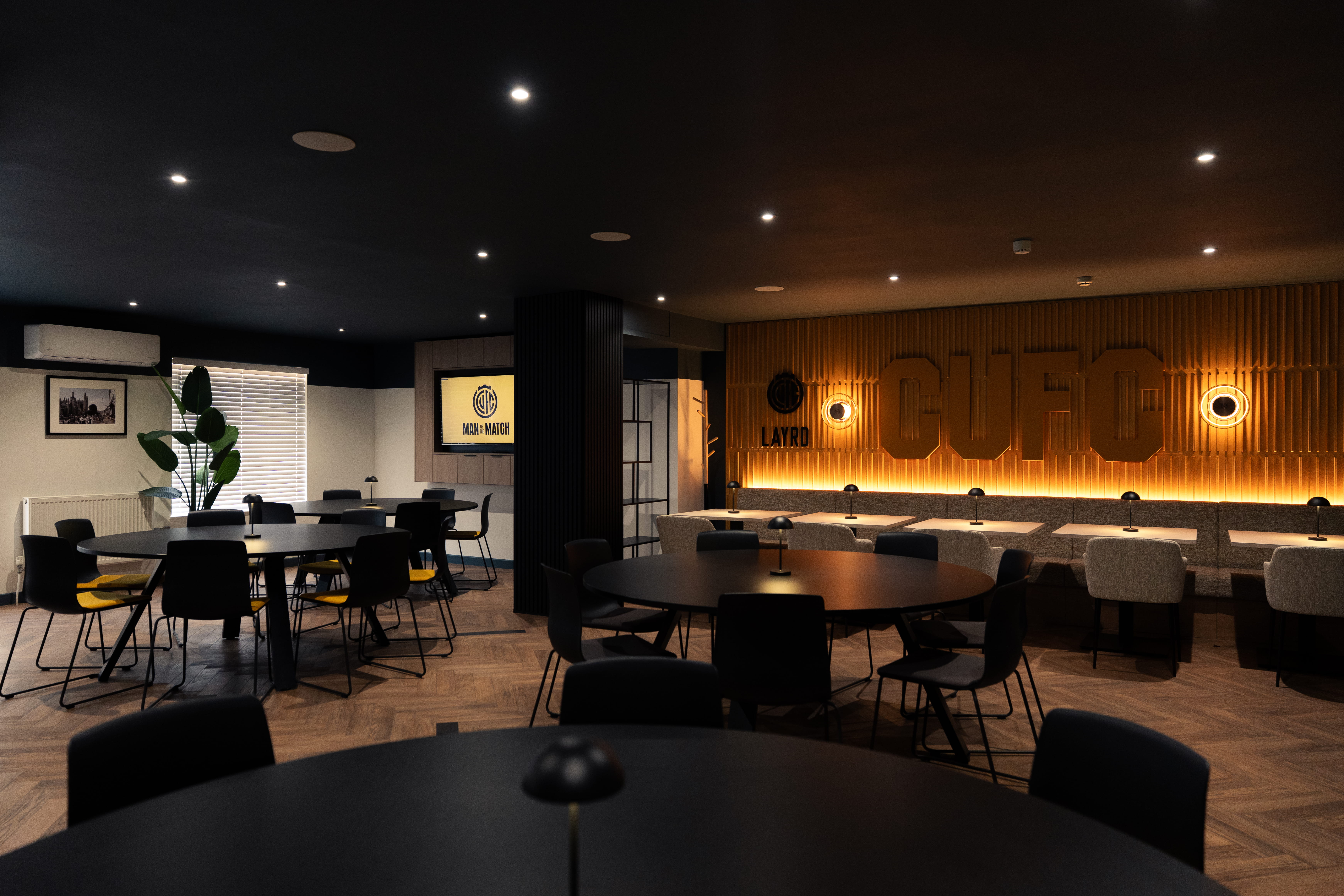 A directors lounge at Ipswich stadium with views to the pitch, showcasing interior design, furniture and bar