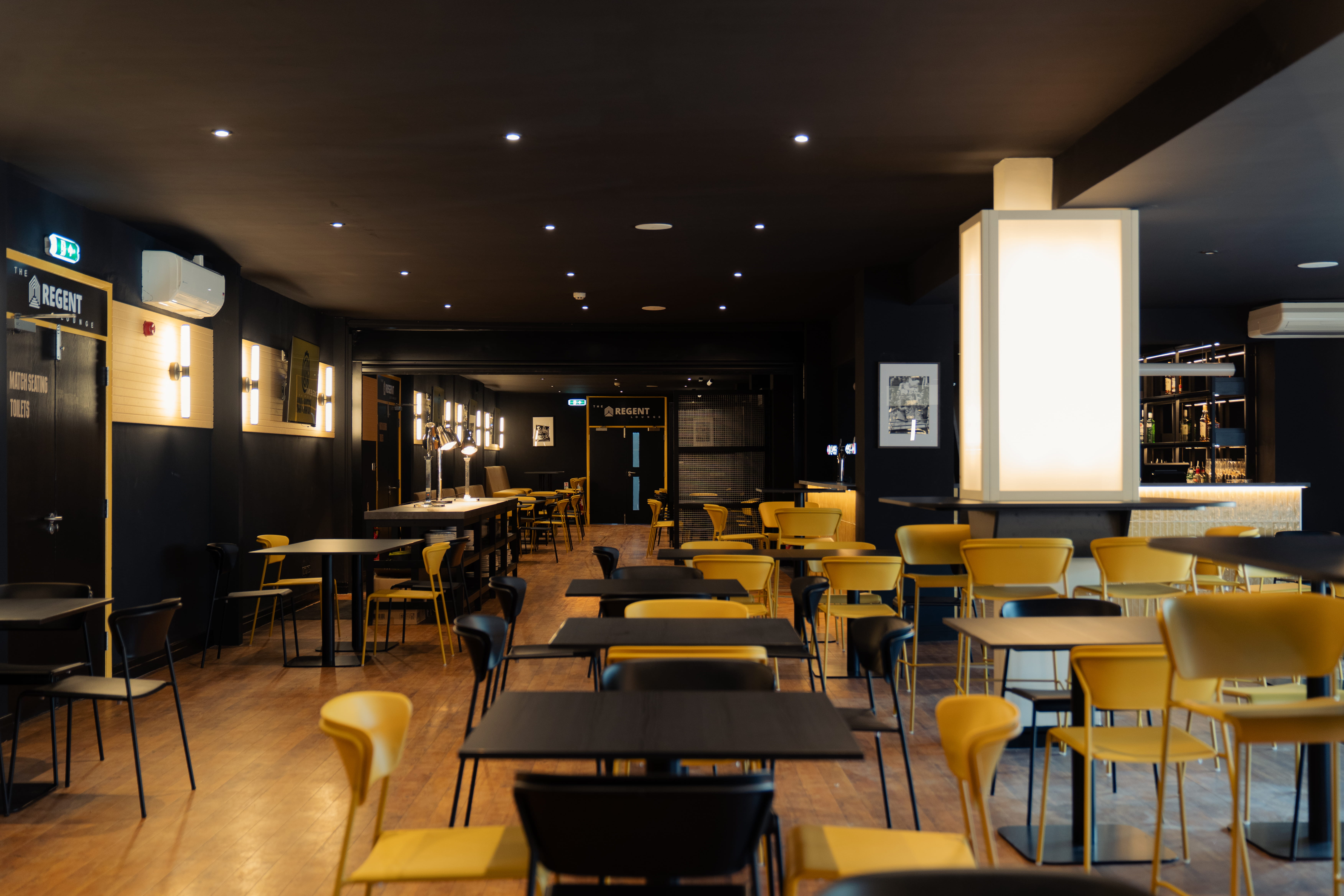 A directors lounge at Ipswich stadium with views to the pitch, showcasing interior design, furniture and bar