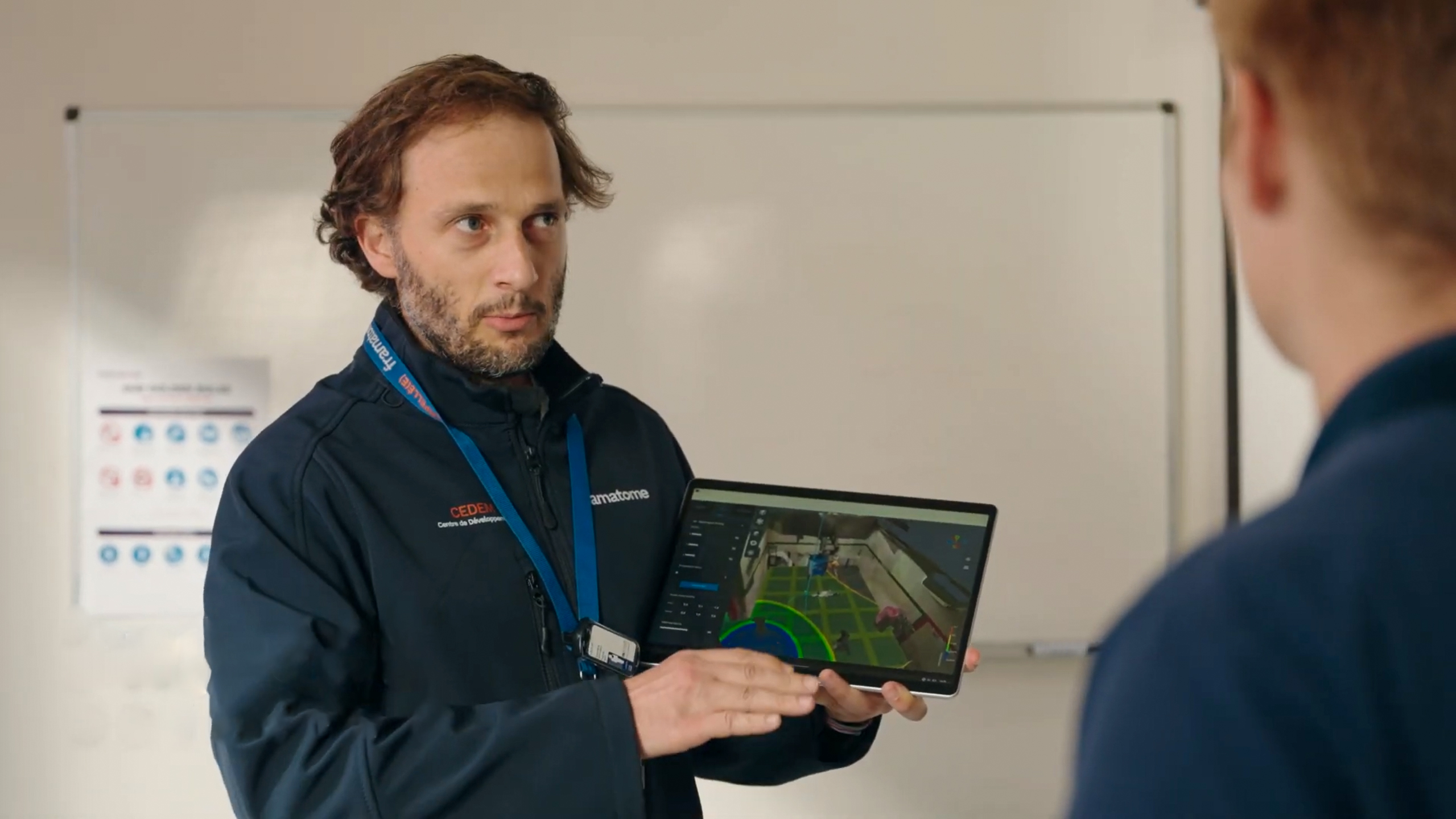 Technicien Framatome présentant sur tablette la cartographie 3D de la radioactivité via H2V Echo lors d’un briefing de préparation à une intervention en environnement nucléaire.