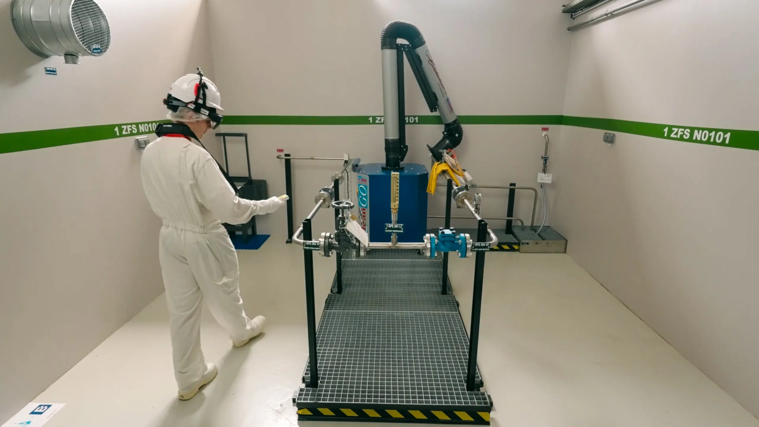 Opérateur en combinaison de protection utilisant un casque H2V Assist pour scanner en 3D une salle technique et mesurer la radioactivité avec un radiamètre ou un dosimètre.