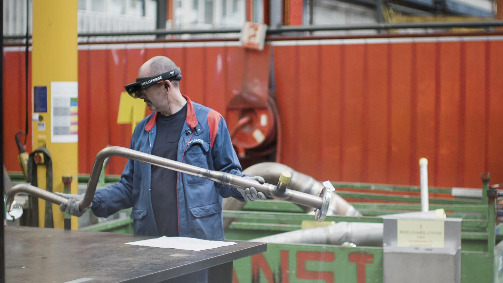 A technician in working blue equipped with HoloForge mixed reality glasses manipulates a metal part in a workshop, illustrating the use of AR/VR for assembly and digital transformation in Industry 4.0.