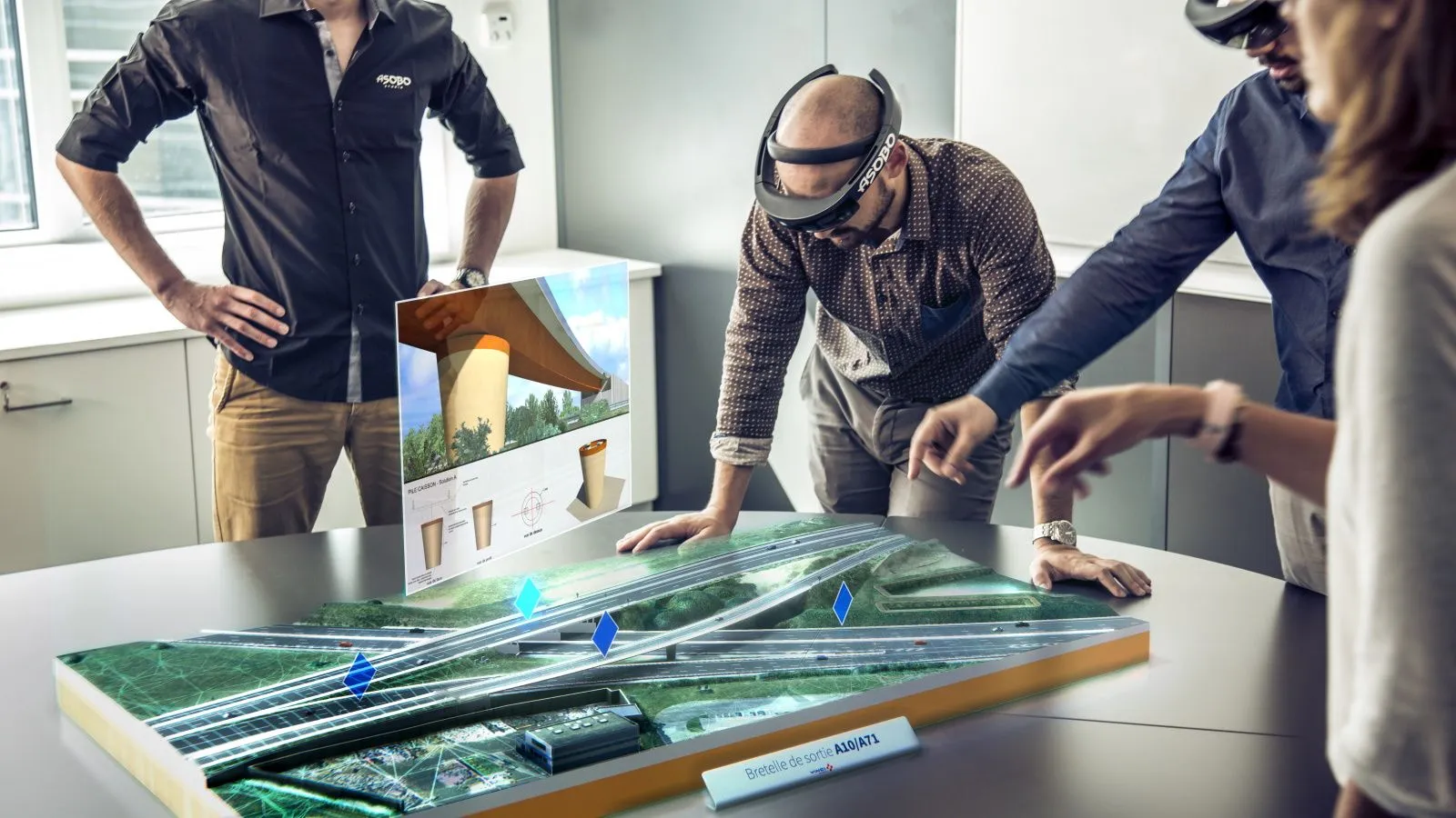 Équipe VINCI Autoroutes utilisant les casques HoloLens pour collaborer autour d’une maquette holographique d’échangeur routier développée par HoloForge Interactive, dans le cadre du projet de visualisation en réalité mixte.