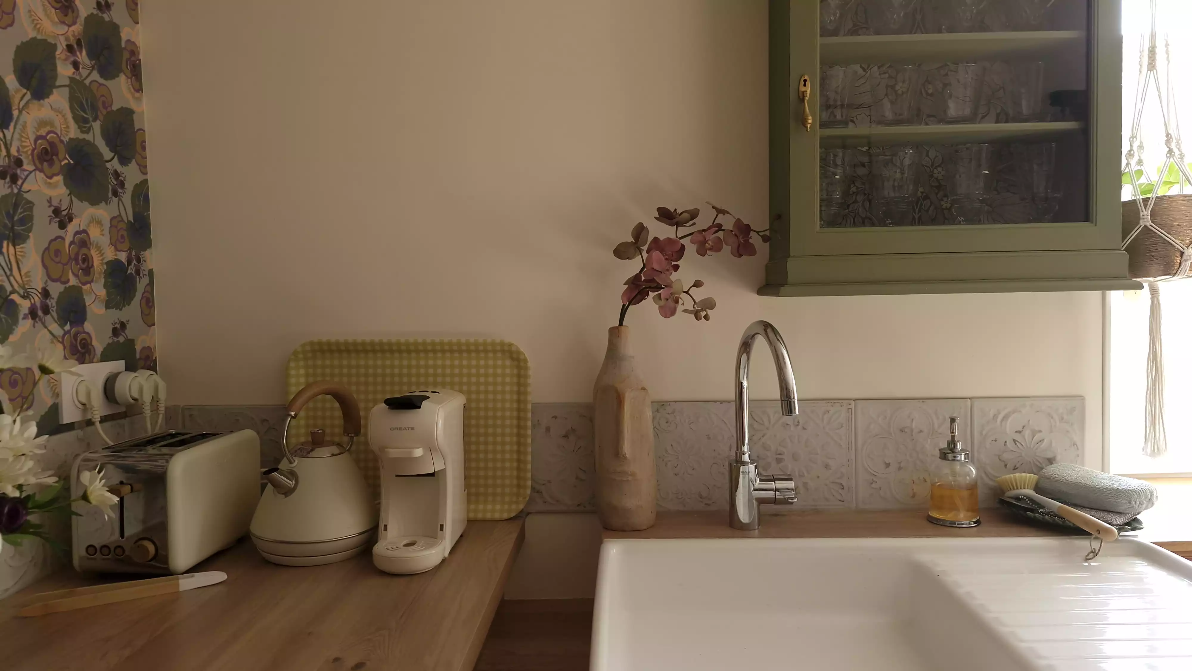 Photo de l'évier de la cuisine et des équipements qui l'entourent : cafetière, grille plain, bouilloire, ...